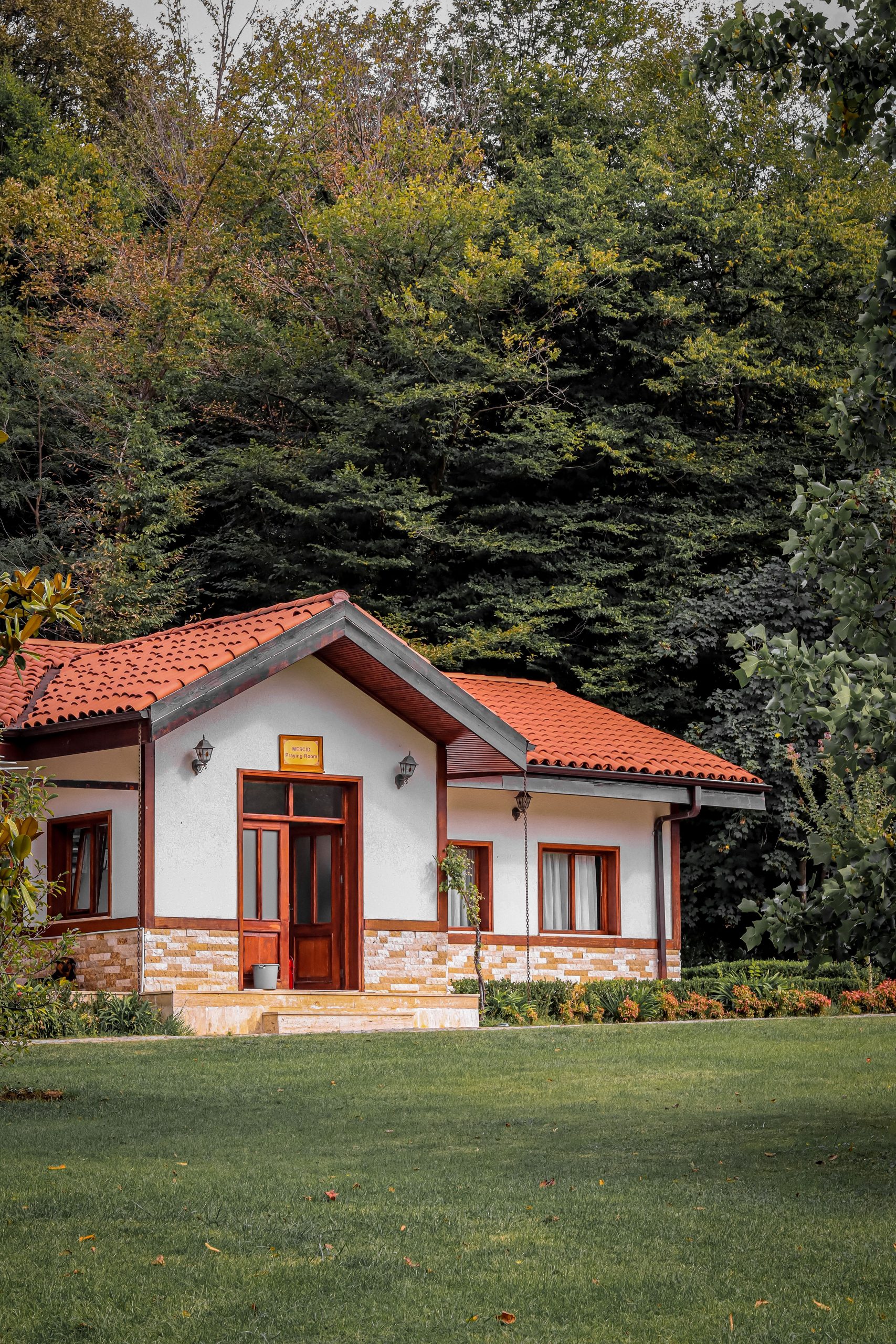 A picturesque cottage with red tiled roof in a verdant forest setting, perfect for tranquil getaways.