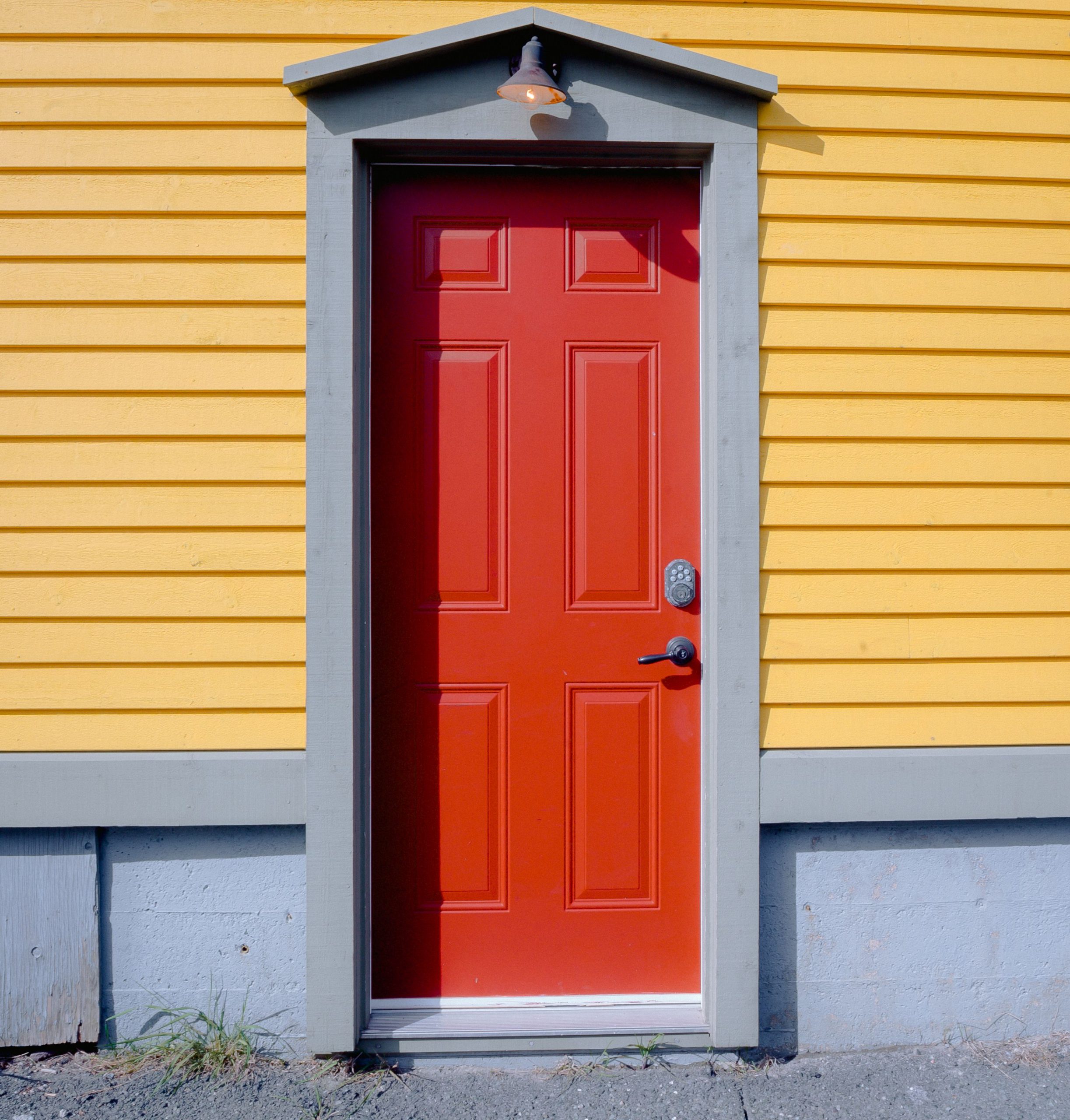 A striking red door contrasting against a yellow wooden wall, showcasing vibrant architecture.