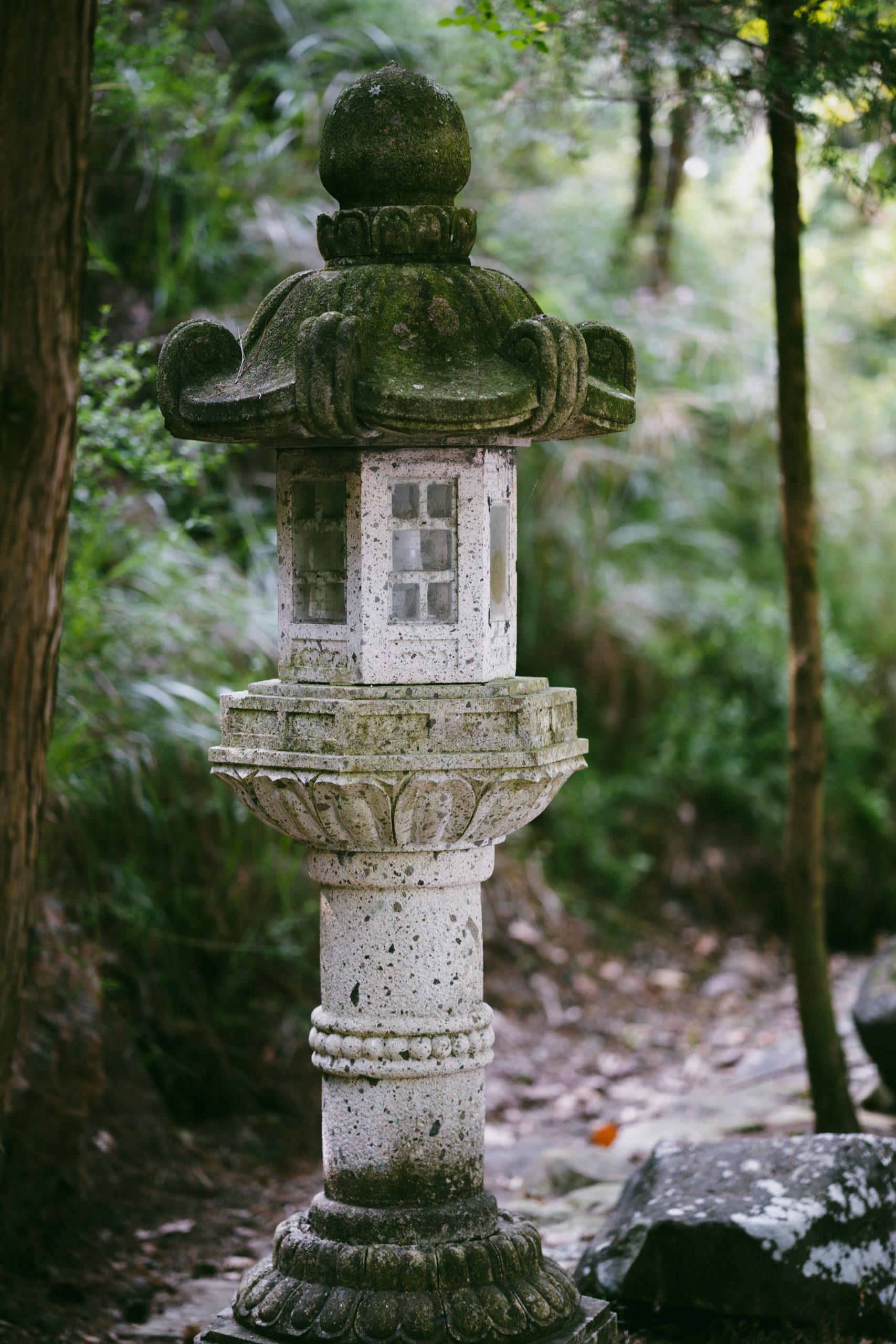 A traditional stone lantern amidst a lush green garden setting, exuding peace.