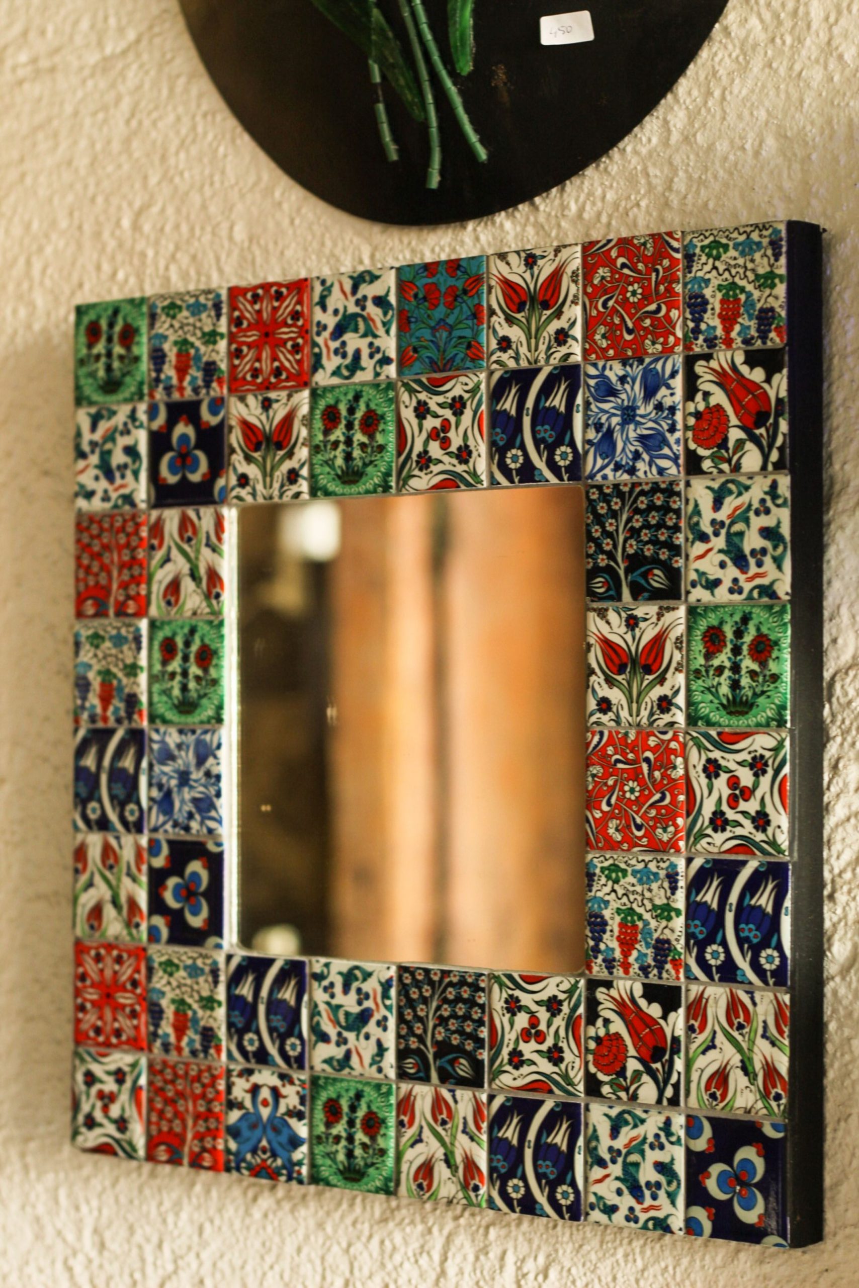 A vibrant wall mirror featuring a colorful mosaic frame with intricate patterns, adding artistic flair to any room.