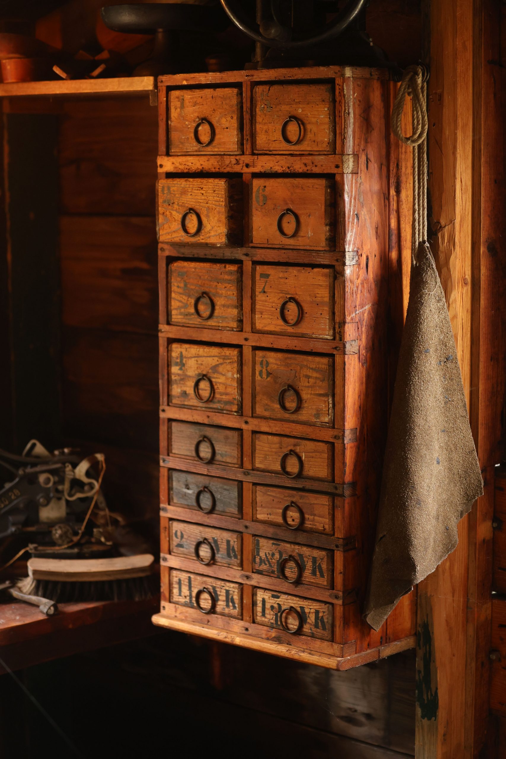 A vintage wooden cabinet with multiple drawers in a warmly lit rustic room.