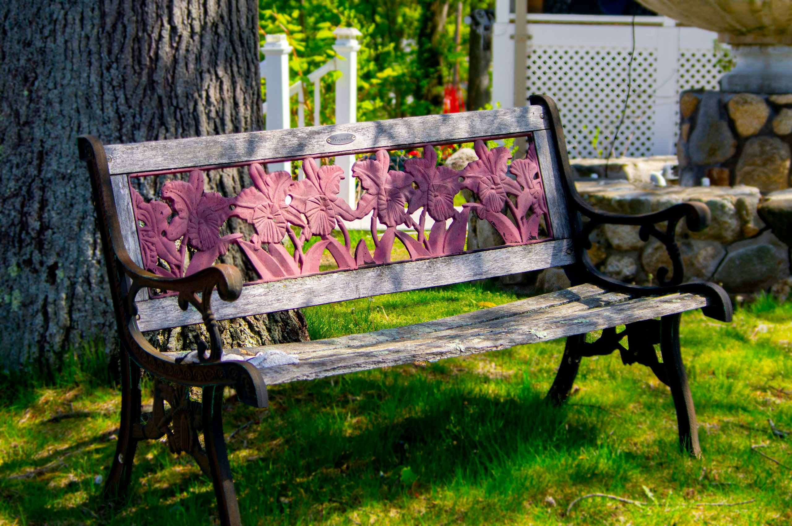 An ornate park bench sitting in a grass field