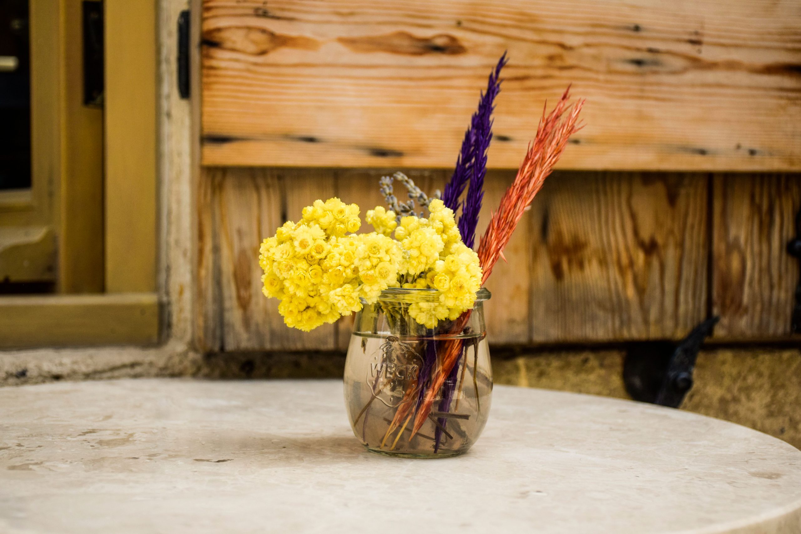 Beautiful rustic floral arrangement in a Mason jar on a stone table in Alaçatı, Türkiye.