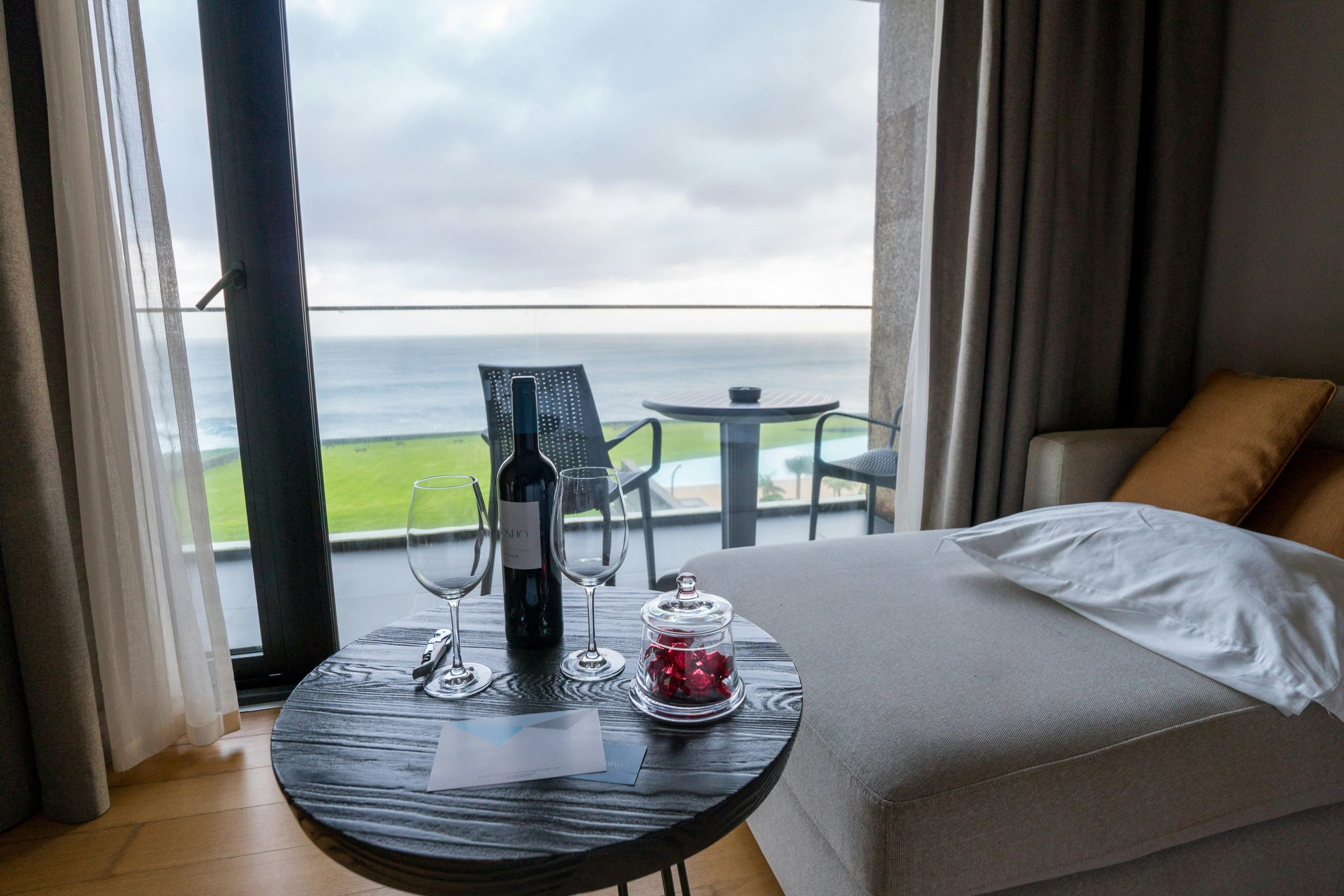 Bottle of wine and glasses on table by ocean view.