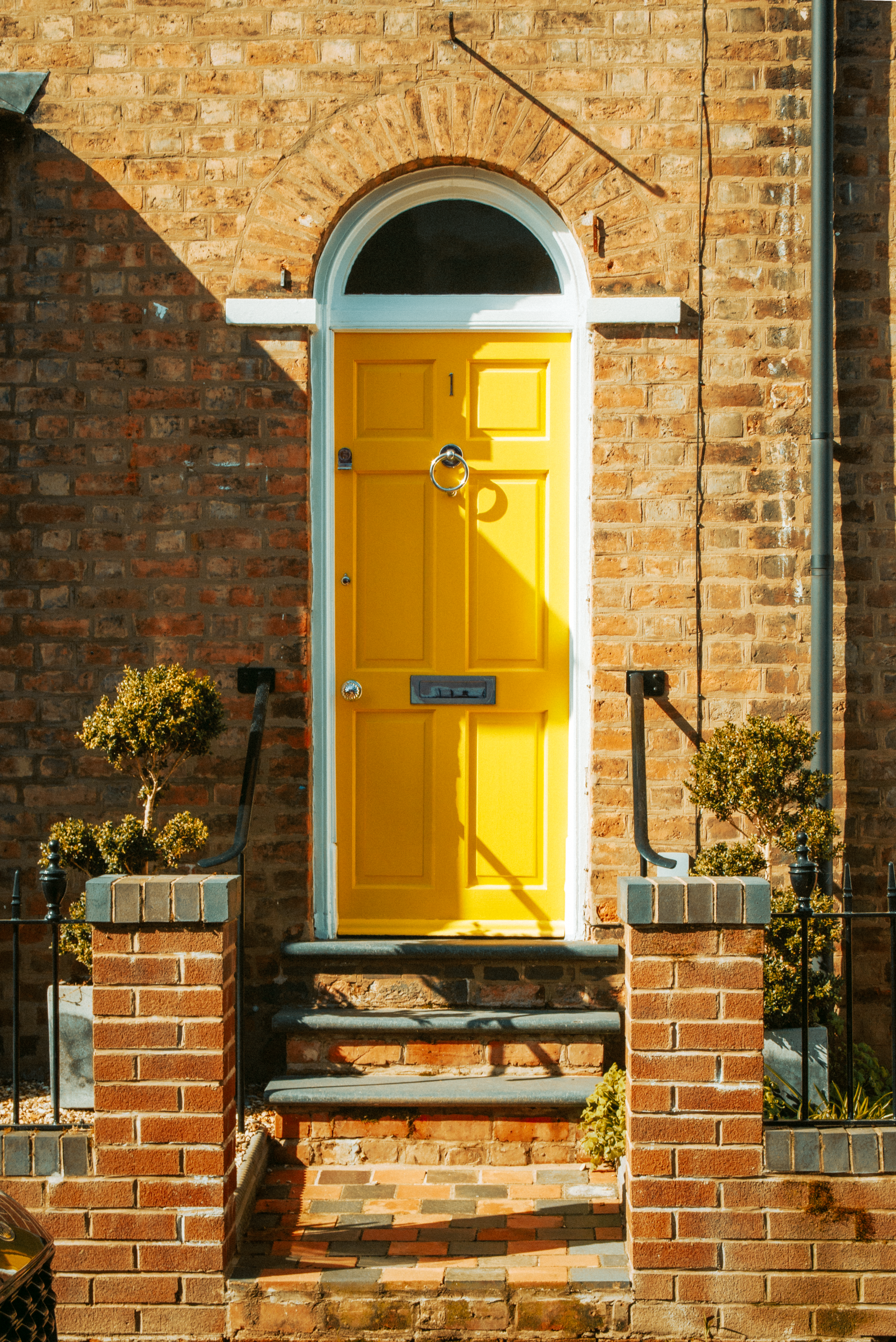 Charming British brick house with a standout yellow door, ideal for architectural themes.