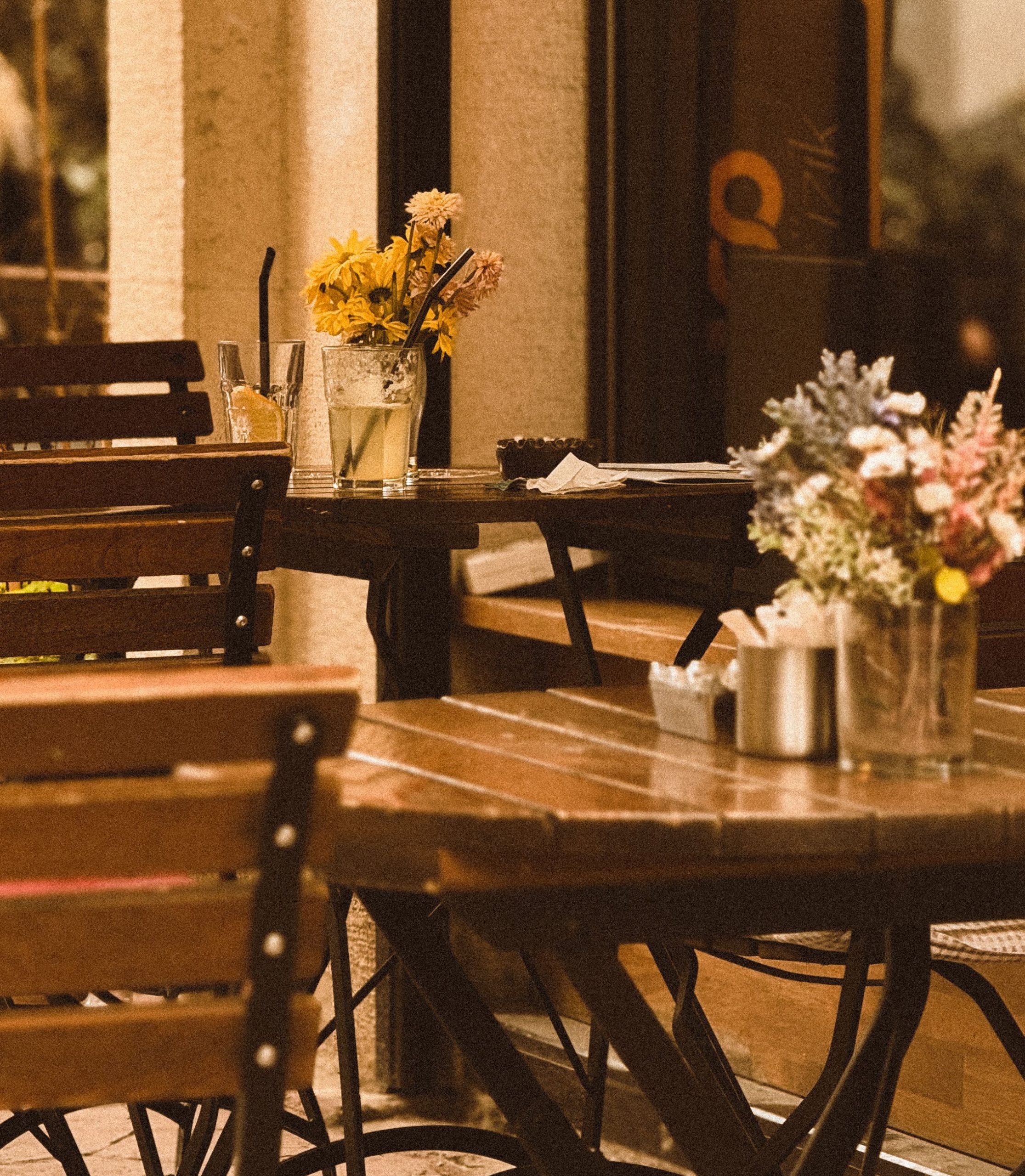 Charming outdoor cafe setting with wooden tables and fresh flowers, perfect for relaxation.