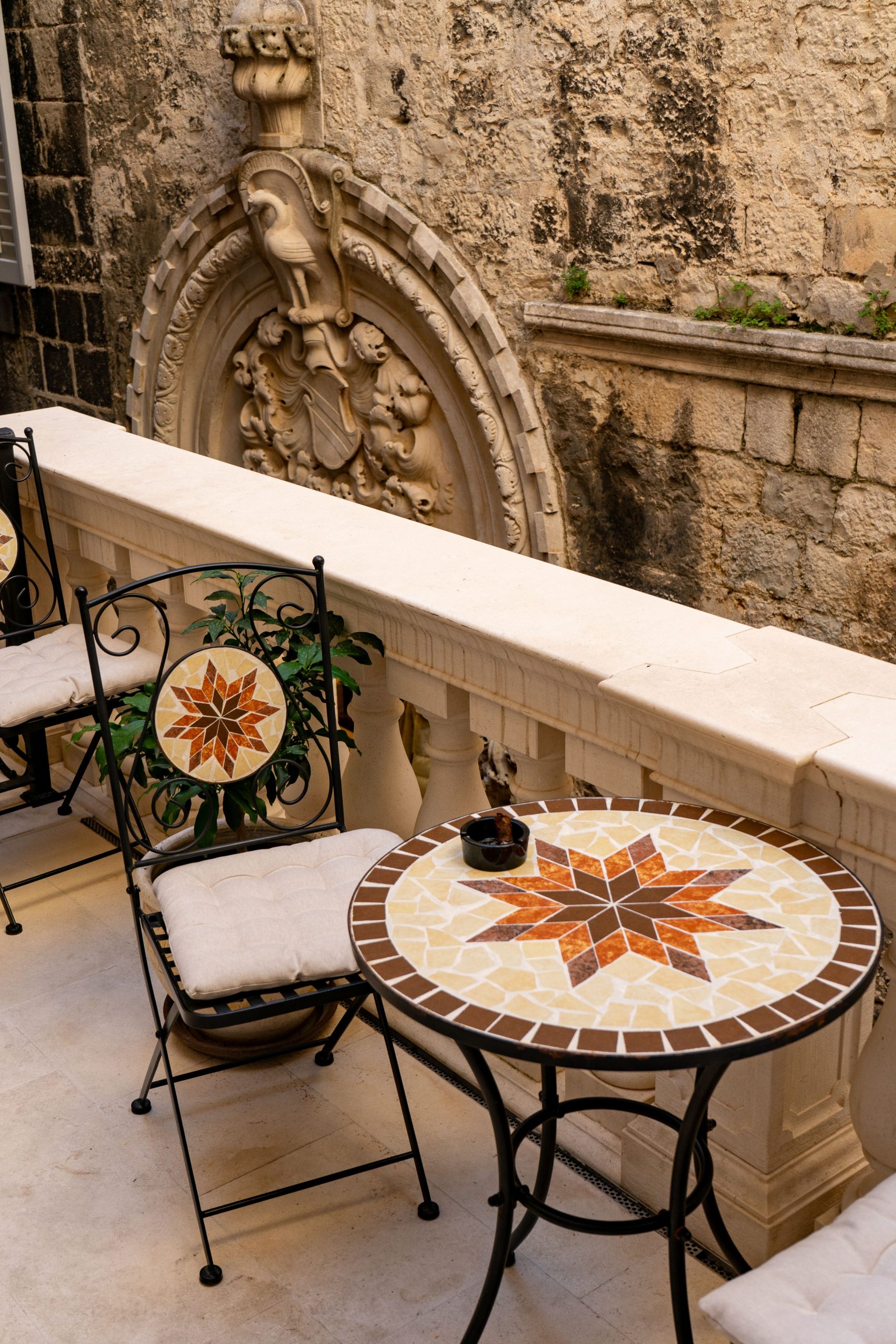 Charming patio with mosaic table in historic Split, Croatia, showcasing intricate stonework.
