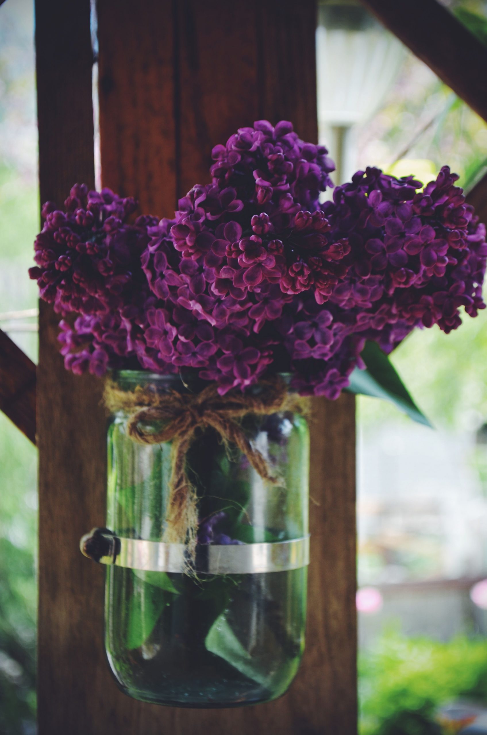 Charming purple lilac flowers in a rustic glass jar, creating a cozy, natural decor piece.