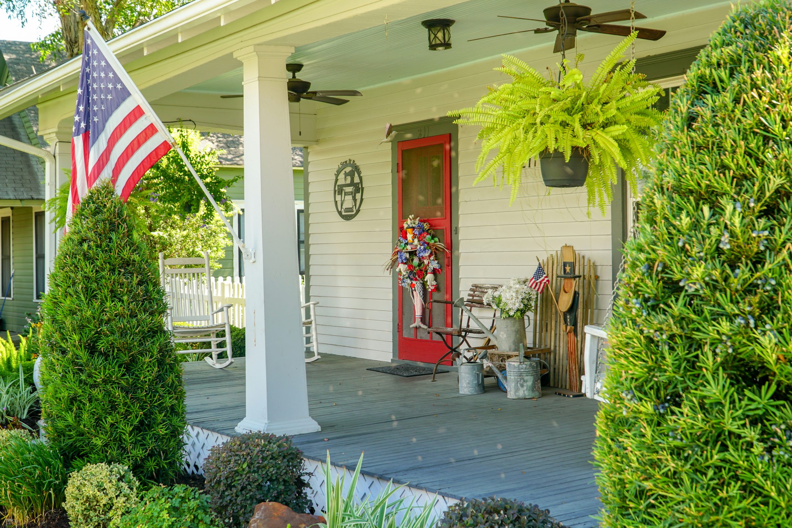 Classic southern American farmhouse front porch decorated for a summer 4th of July celebration.