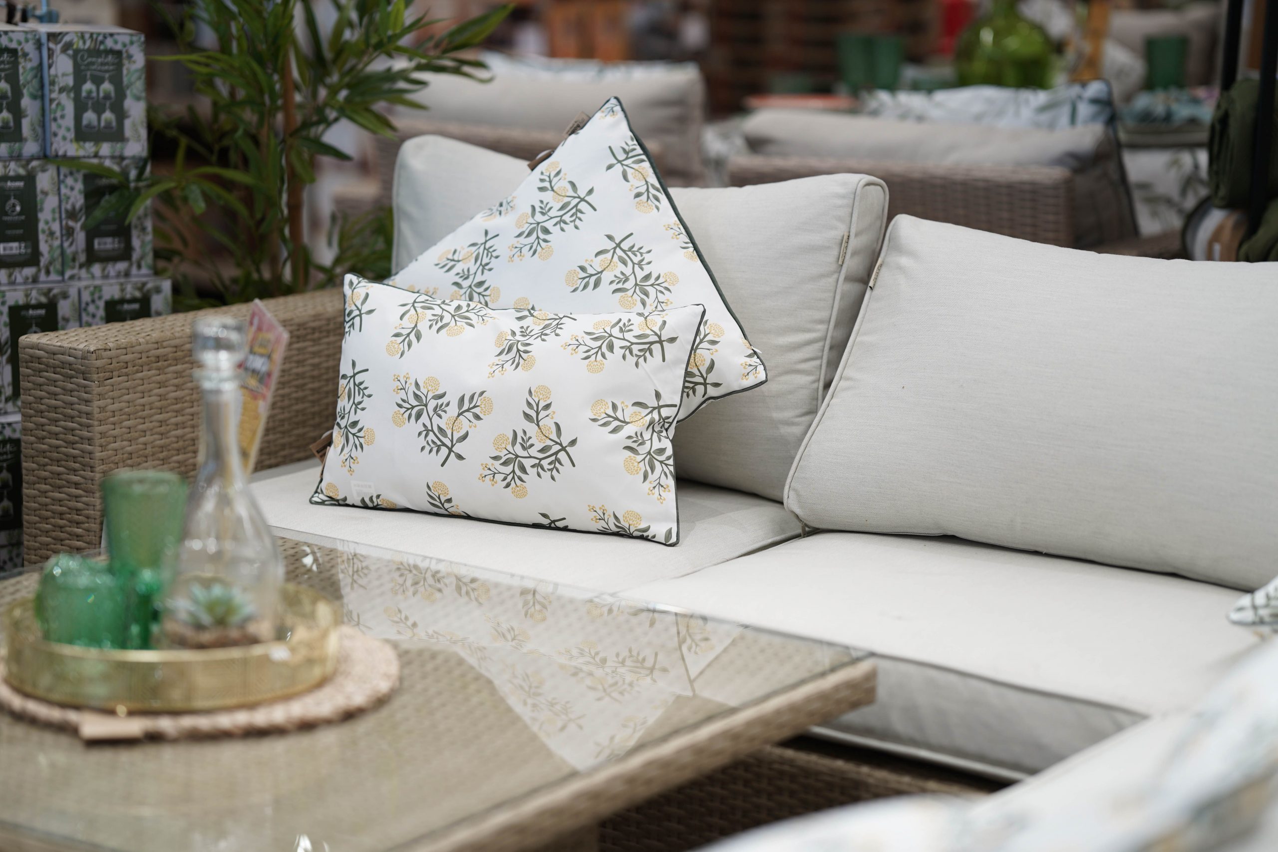 Cozy outdoor patio setting featuring stylish floral-patterned cushions on a wicker sofa and glass table.