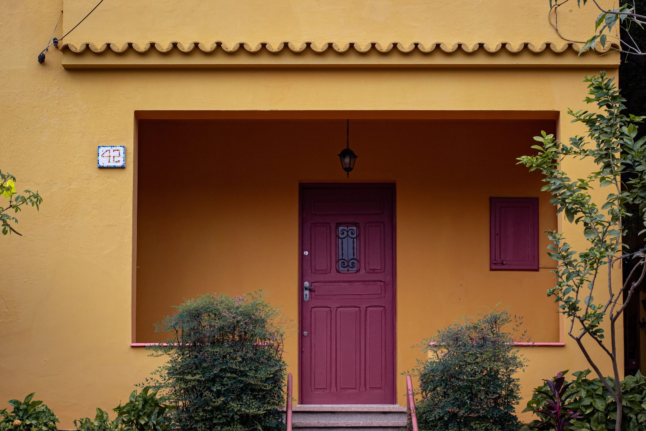 Detailed view of a colorful yellow house with a bold red door in São Paulo, Brazil.