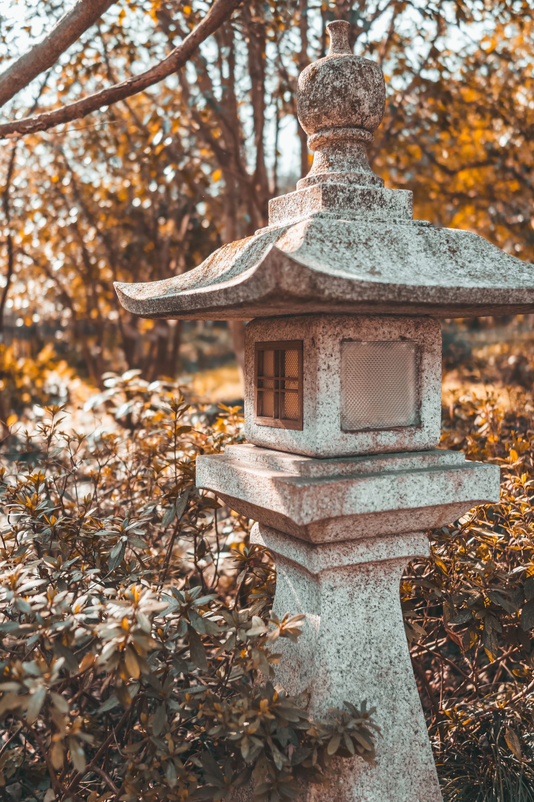 Elegant stone lantern in a Japanese garden surrounded by autumn foliage.