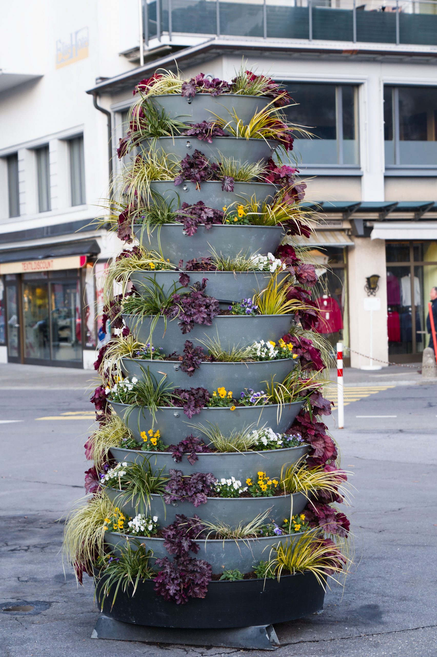 Elegant tiered planter with vibrant plants in Swiss cityscape