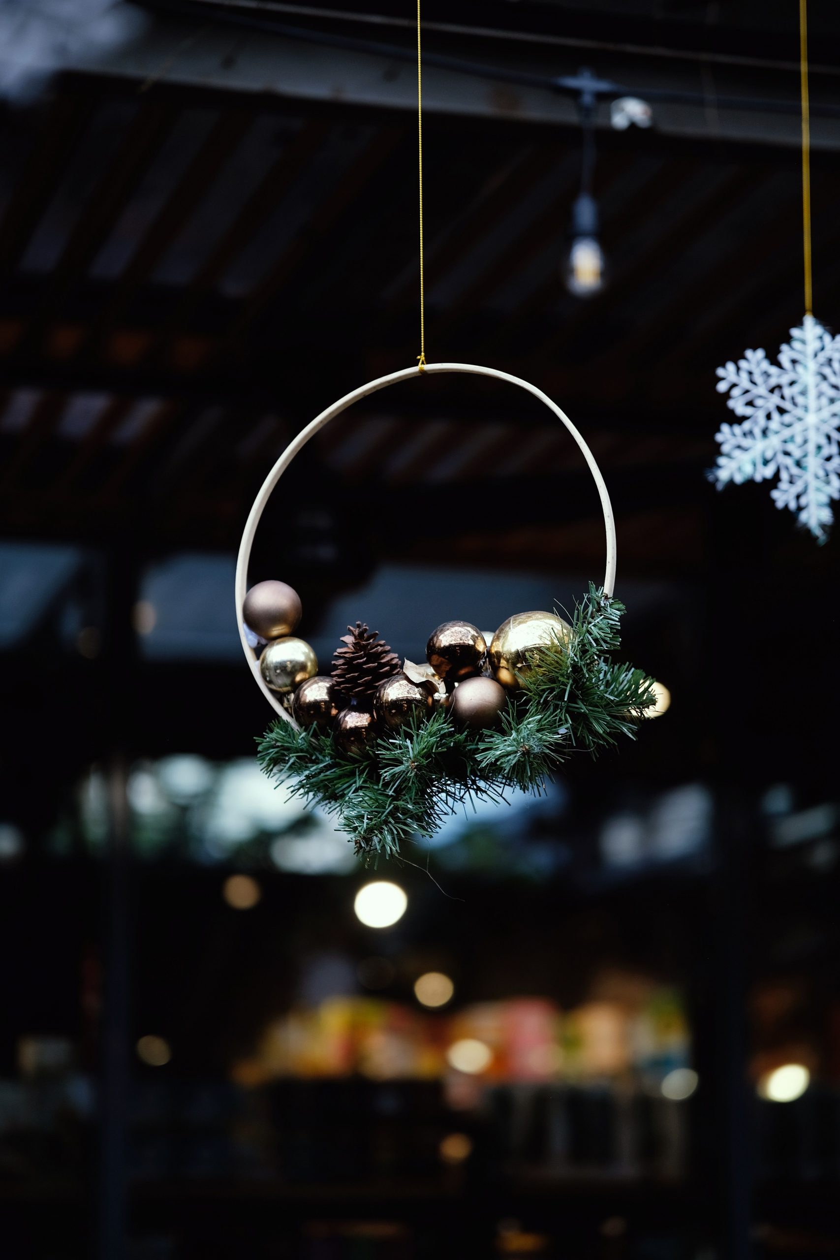 Hanging holiday wreath adorned with pinecones and baubles in a cozy setting.
