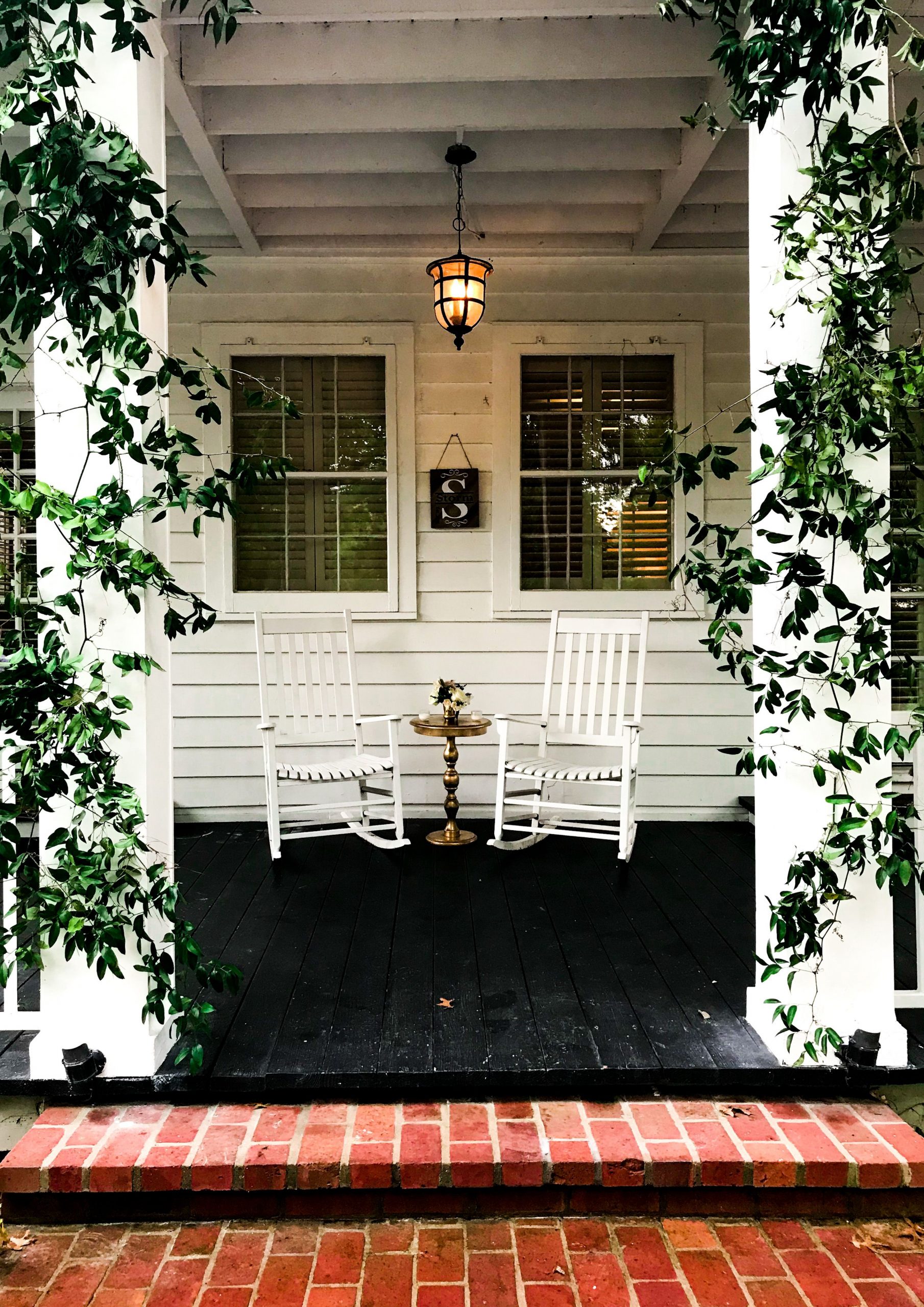 Inviting porch with rocking chairs, wooden details, and lush greenery for a relaxing atmosphere.