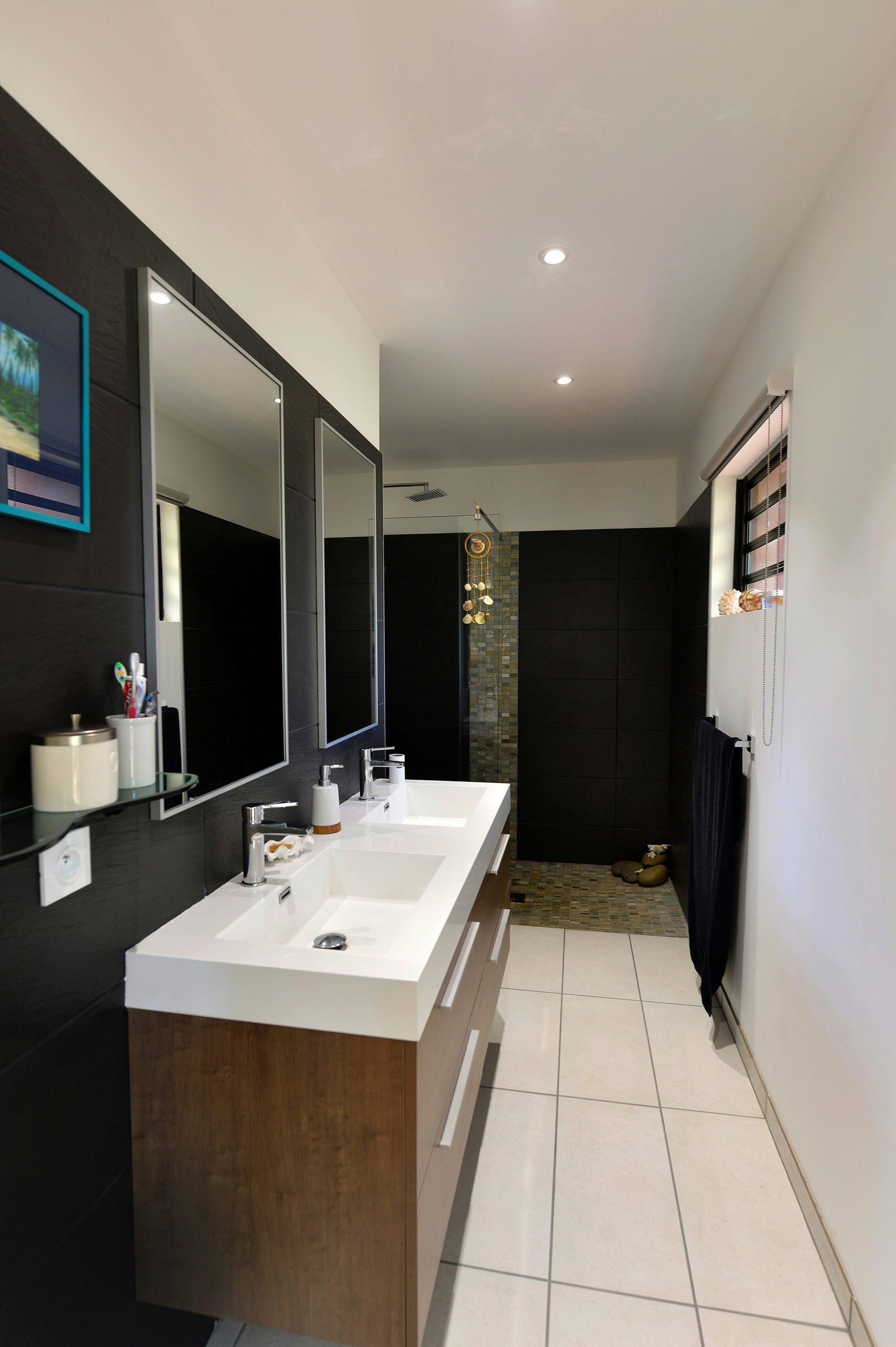 Modern bathroom with double vanity, mirrors, and shower.