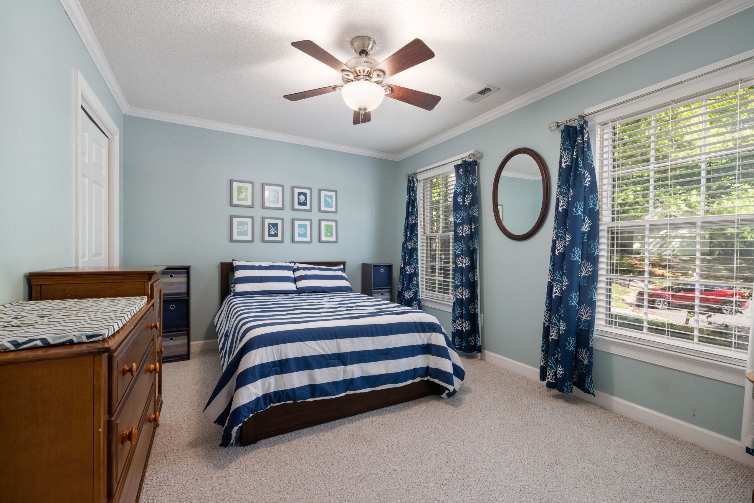 Stylish bedroom interior with blue striped bedding and natural light.