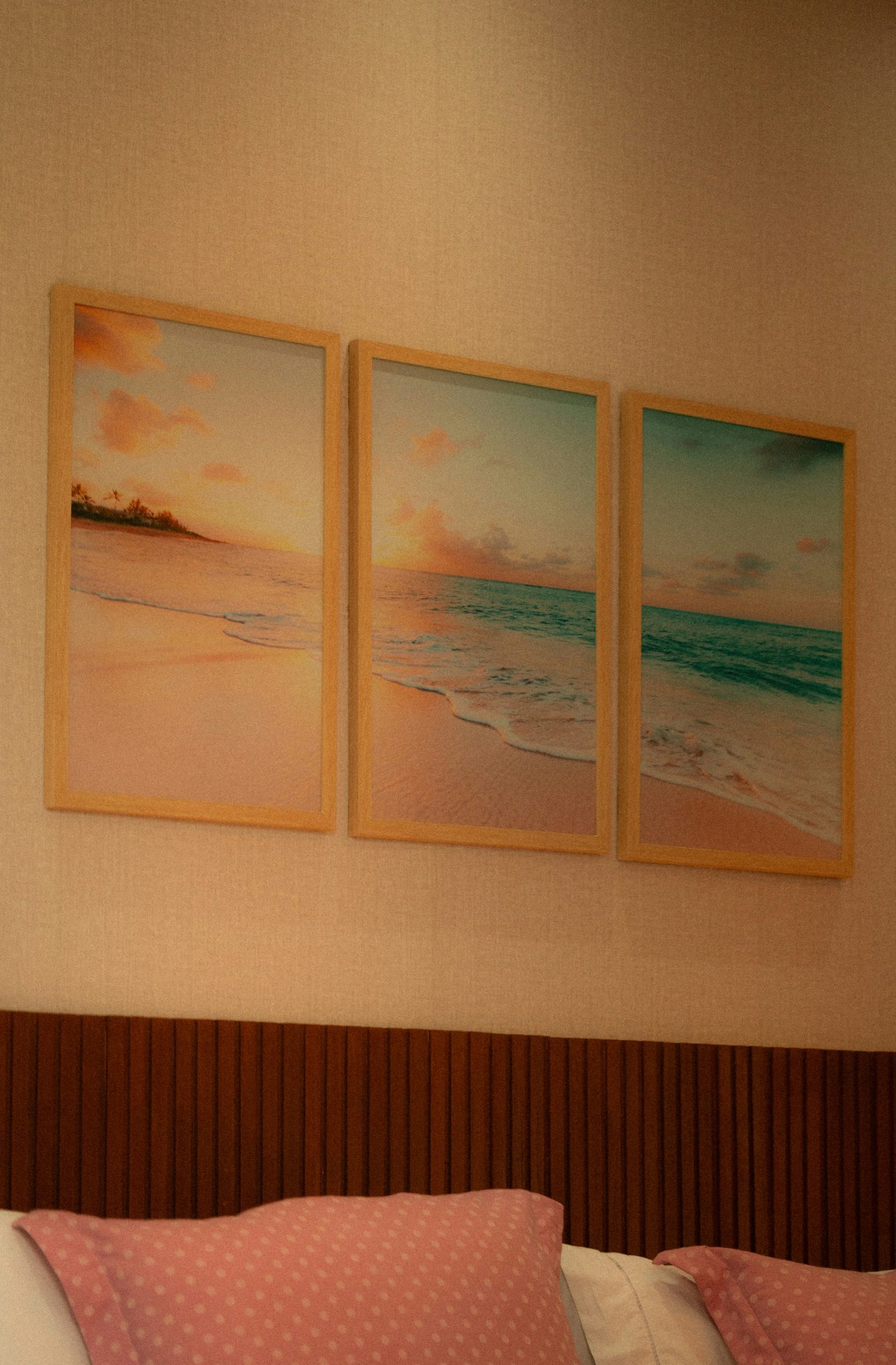 Three framed beach sunset artworks above a headboard