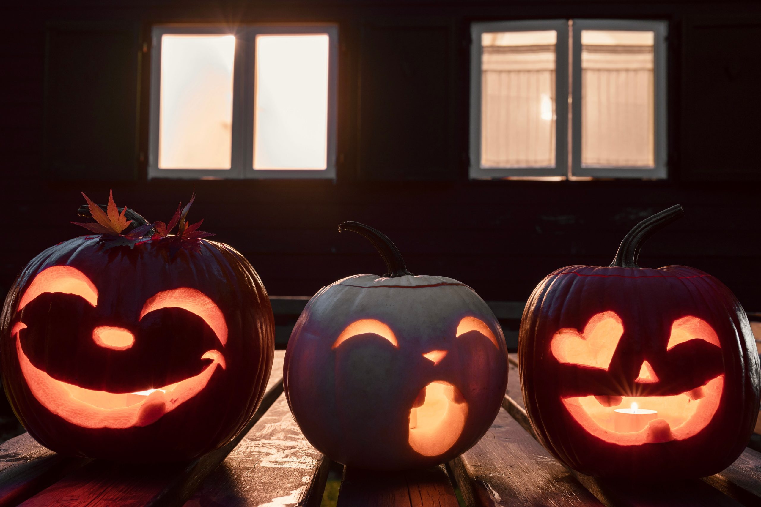 Three illuminated jack-o'-lanterns with carved faces, perfect for Halloween ambiance.