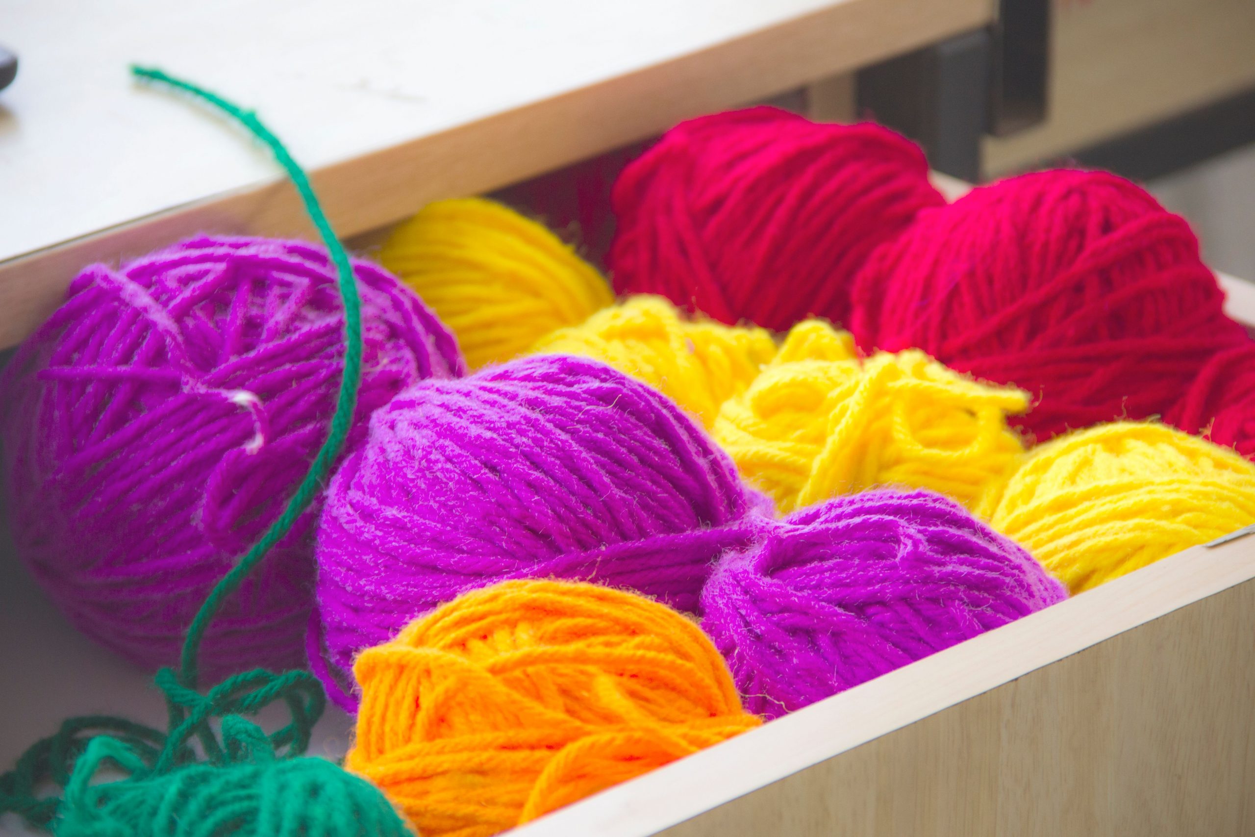 Vibrant and colorful yarn balls neatly organized in a drawer, perfect for knitting and textile projects.