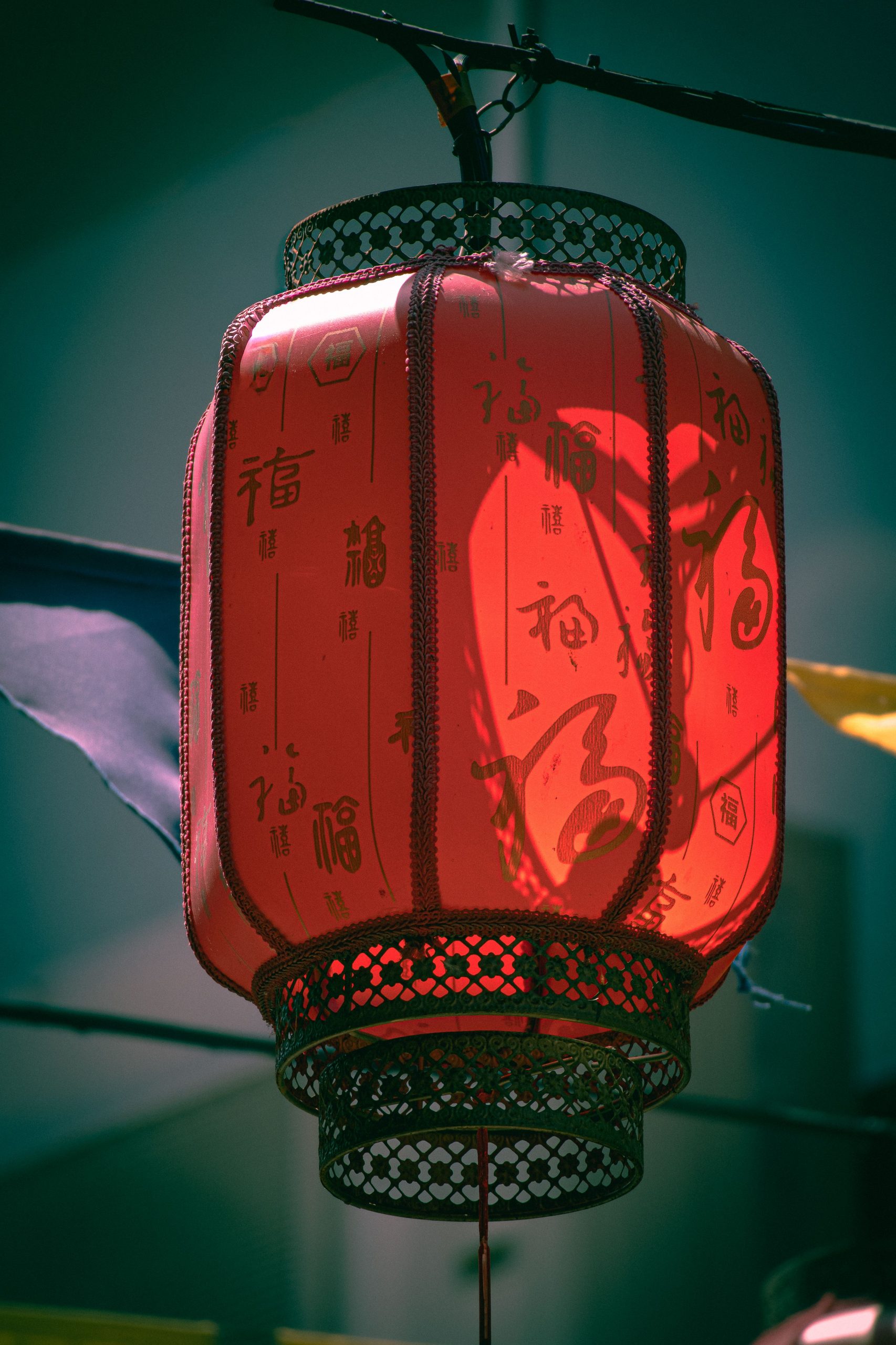 Vibrant red Chinese lantern with intricate patterns hanging outdoors.
