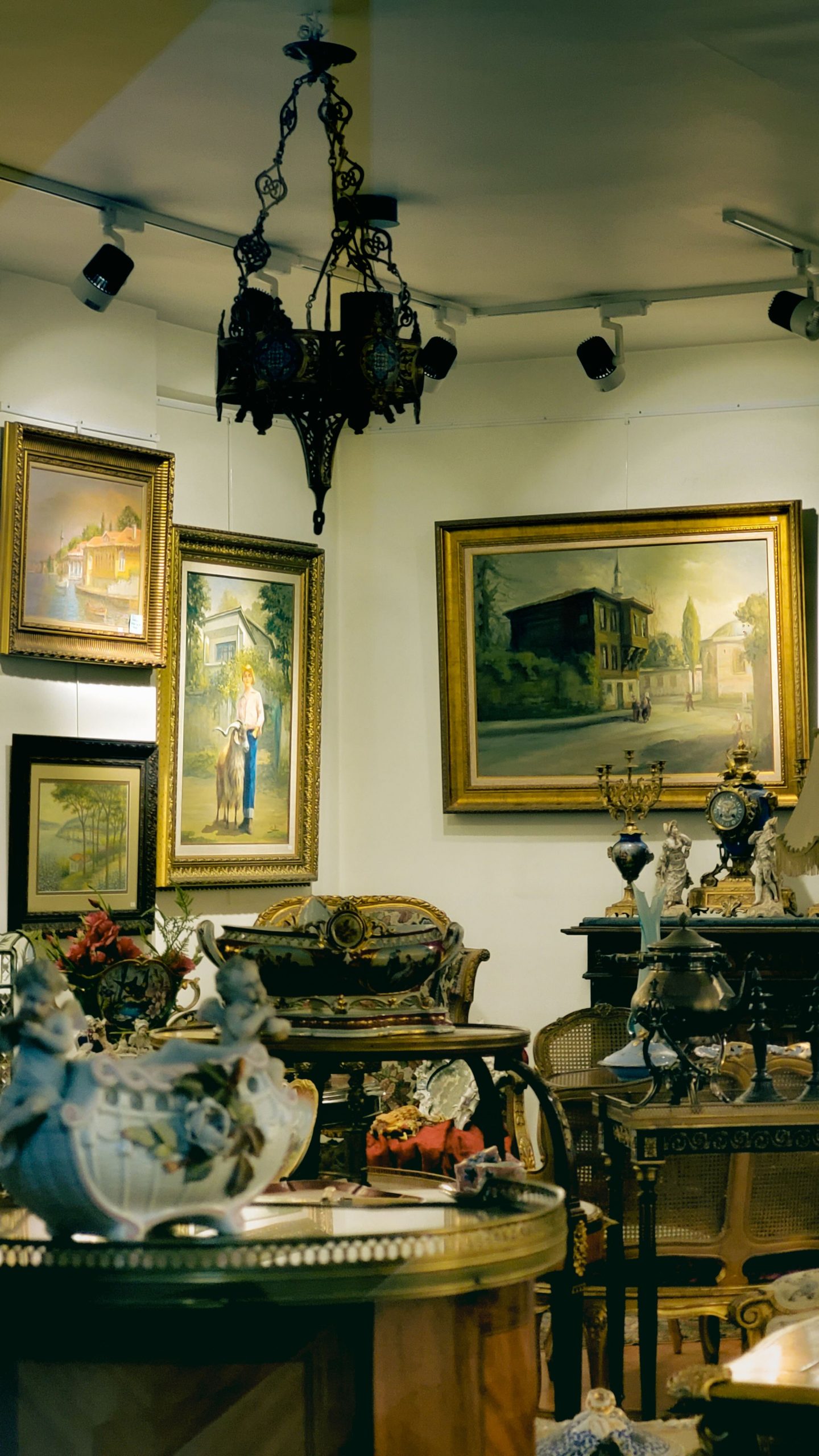 A beautifully decorated room with paintings, antique furniture, and a chandelier, creating a vintage interior design vibe.