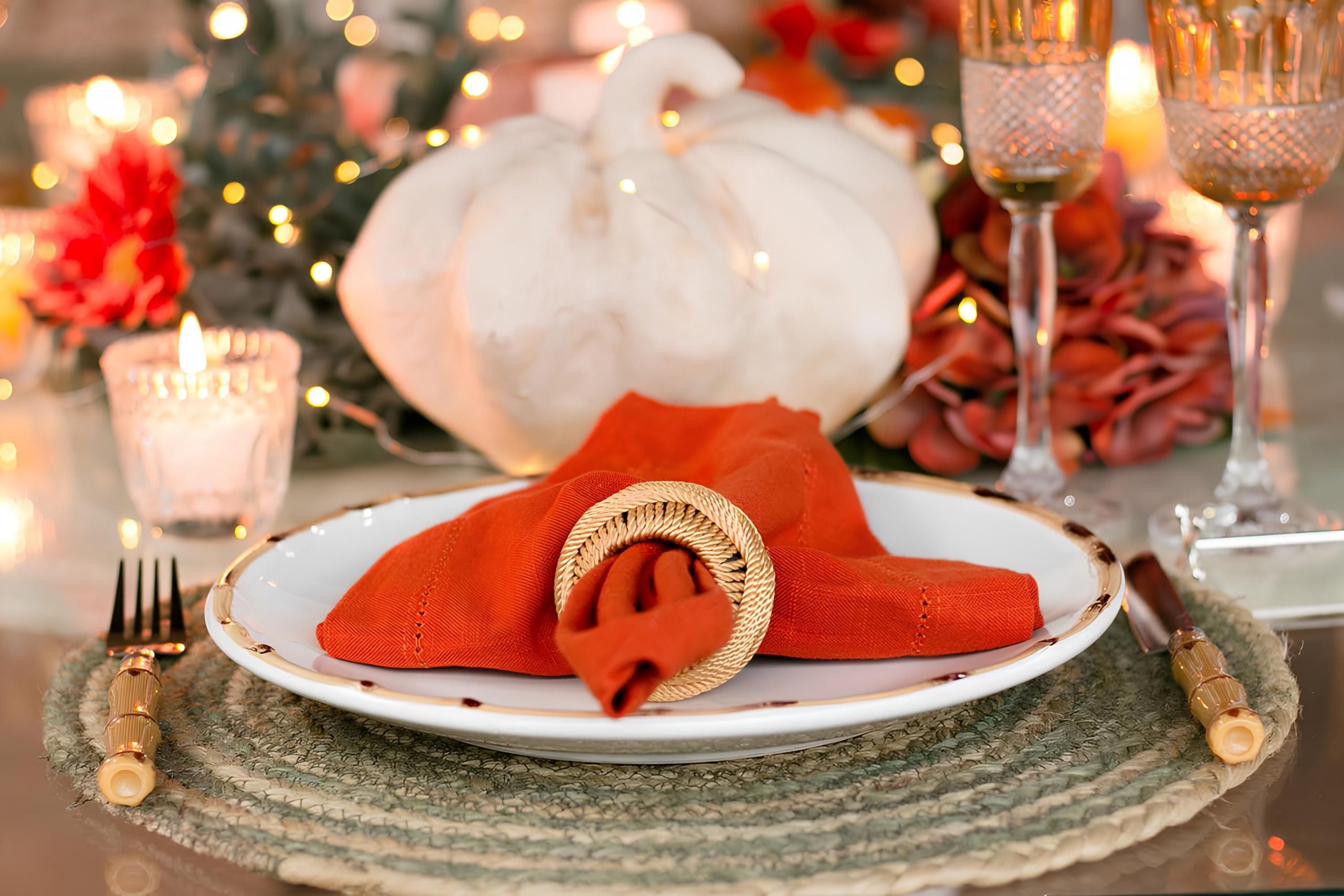 A beautifully set autumn table with pumpkin decor and warm lighting for cozy gatherings.