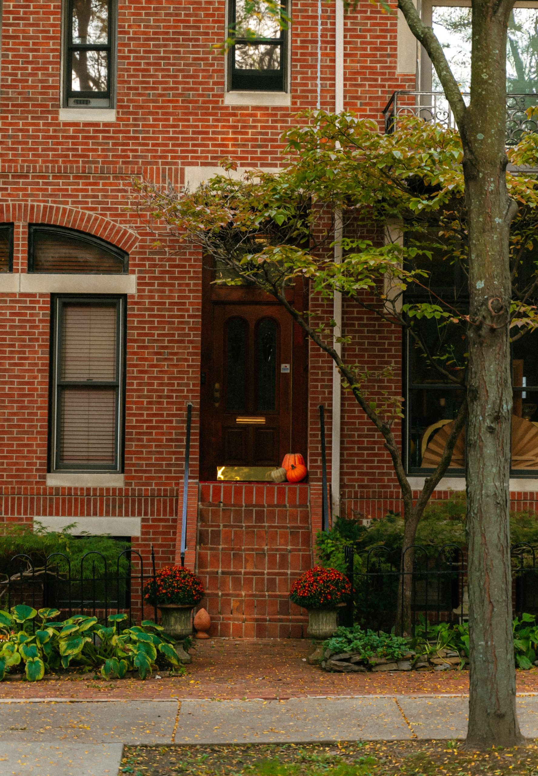 A classic brick home in Cincinnati adorned with fall decorations and a carved pumpkin on the steps.