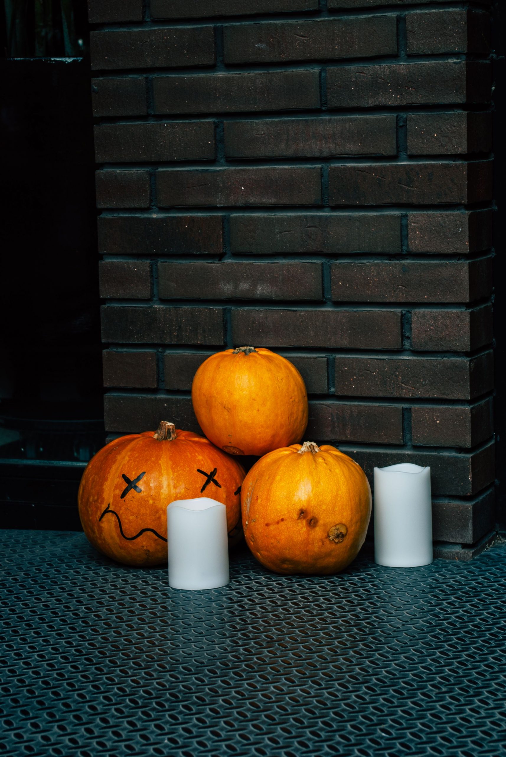 A collection of carved pumpkins and candles against a brick wall, perfect for Halloween.