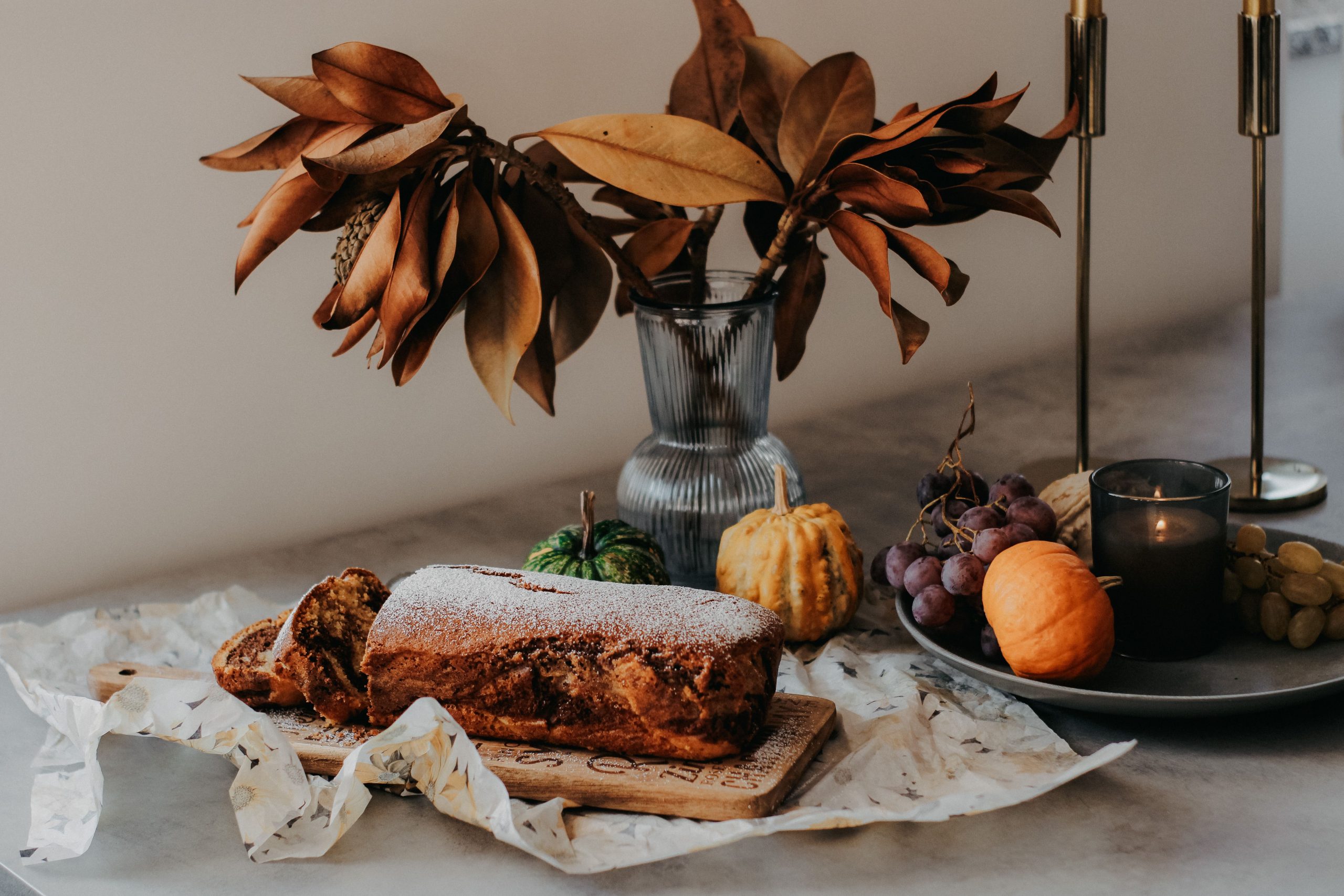 A cozy autumn still life featuring rustic bread, gourds, and dried leaves.