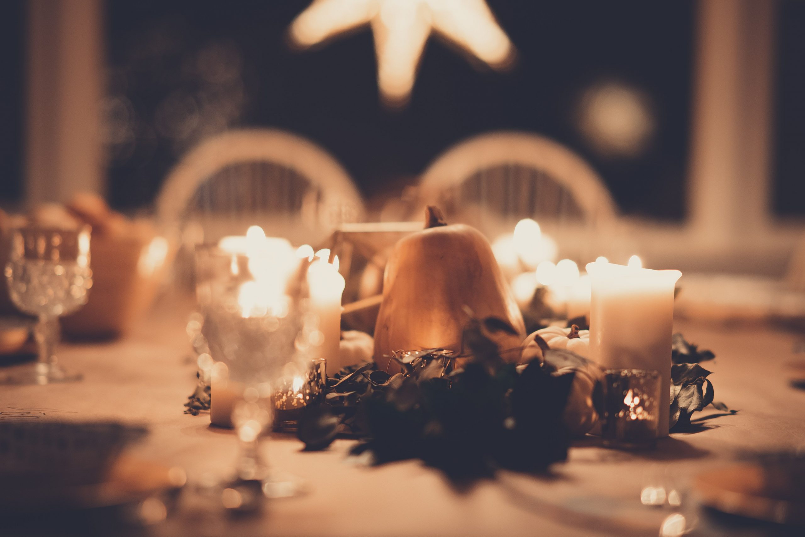A cozy, elegant Thanksgiving table with candles and pumpkins creating a warm ambiance.