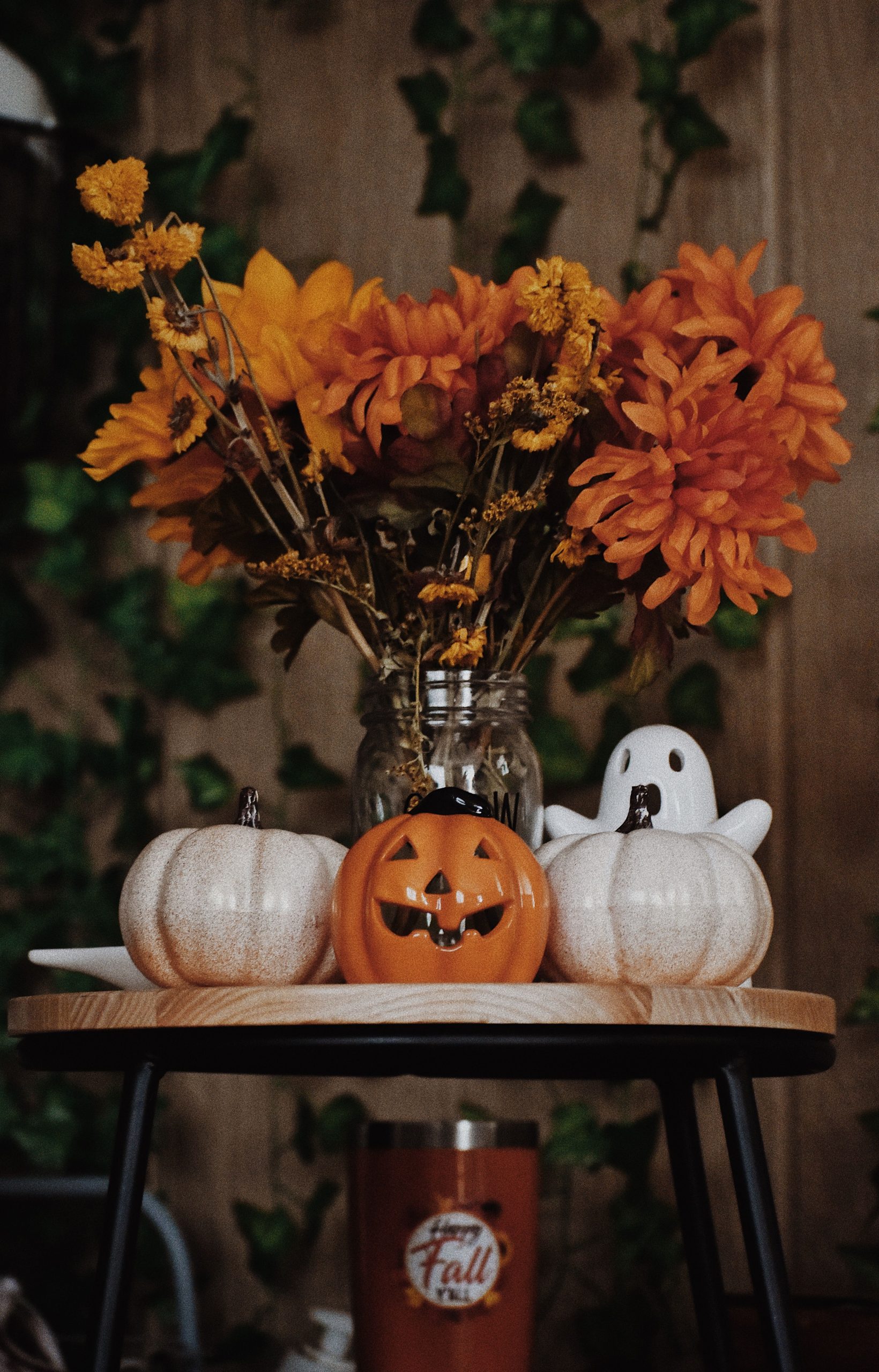 A cozy Halloween arrangement featuring pumpkins, orange flowers, and festive decor on a wooden table.