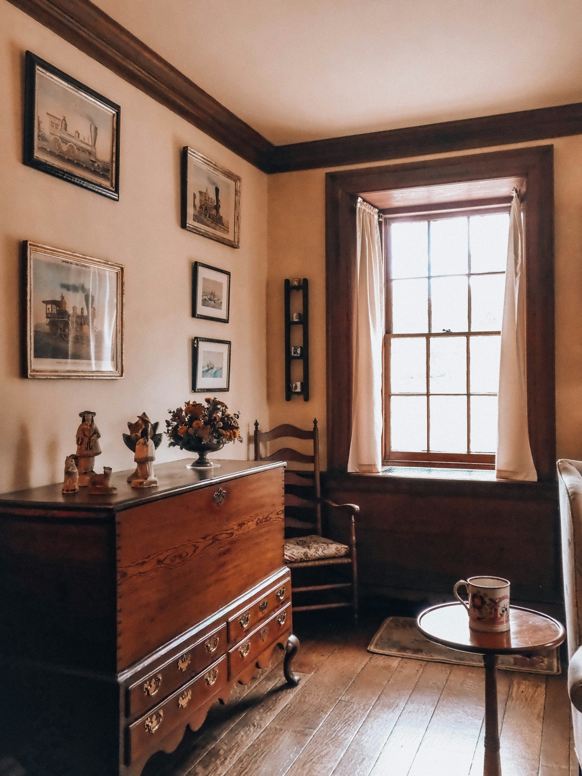 A cozy, old-fashioned room with wooden furniture and framed art.