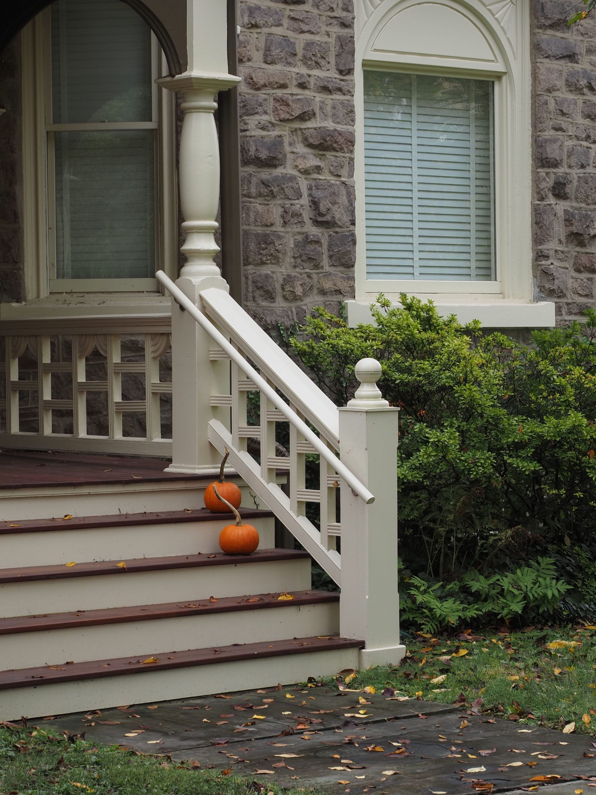 A cozy stone house porch decorated with pumpkins and fall leaves ideal for seasonal themes.
