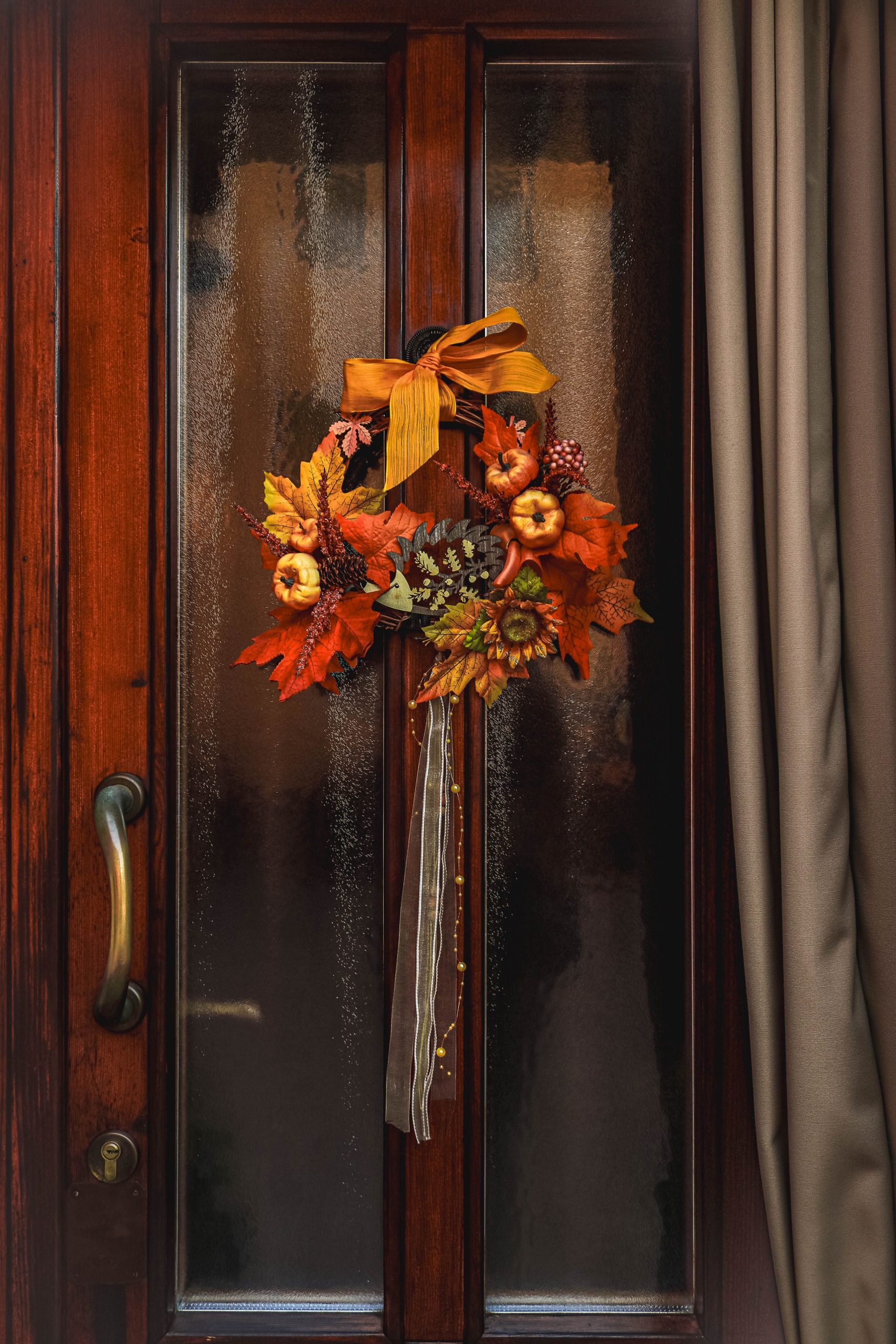A decorative fall wreath adorns a glass door, creating a cozy autumn ambiance.