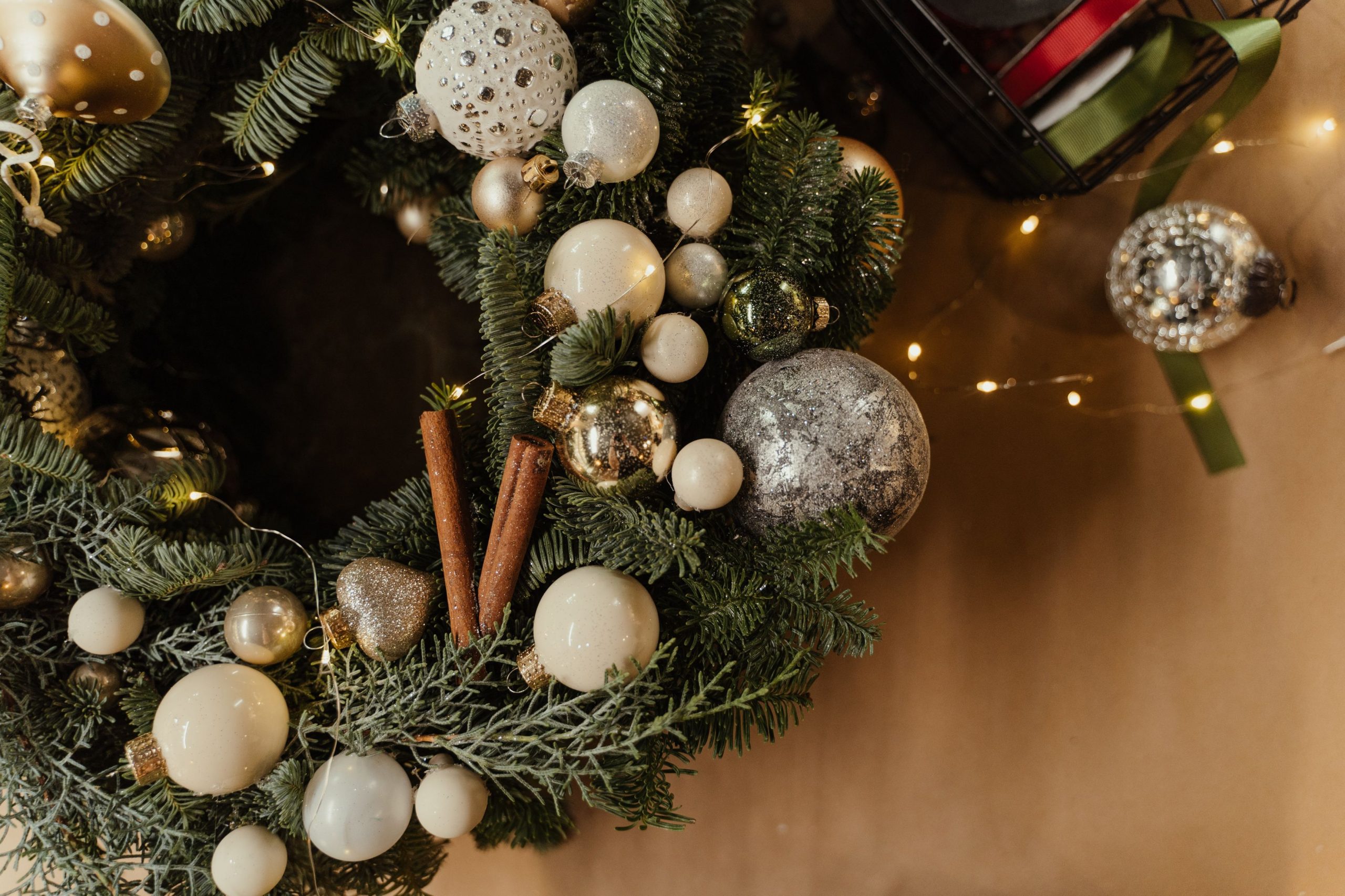 A festive Christmas wreath adorned with baubles, cinnamon sticks, and twinkling lights, perfect for holiday decor.