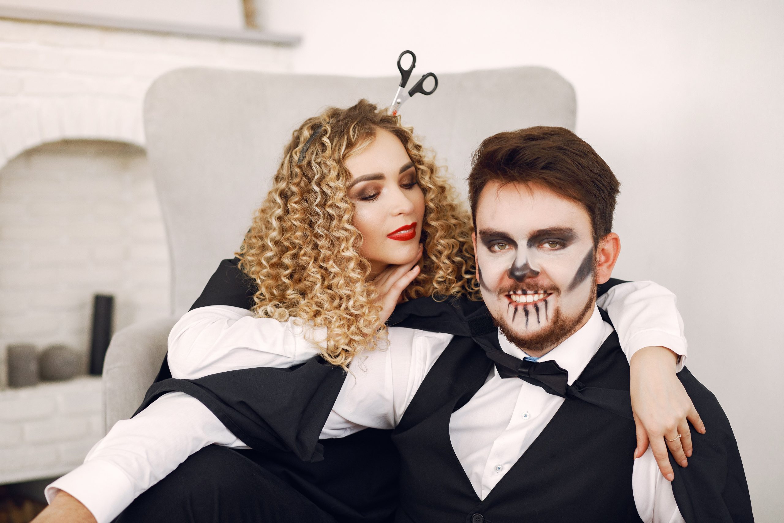 A loving couple dressed in creative Halloween costumes inside a cozy room.