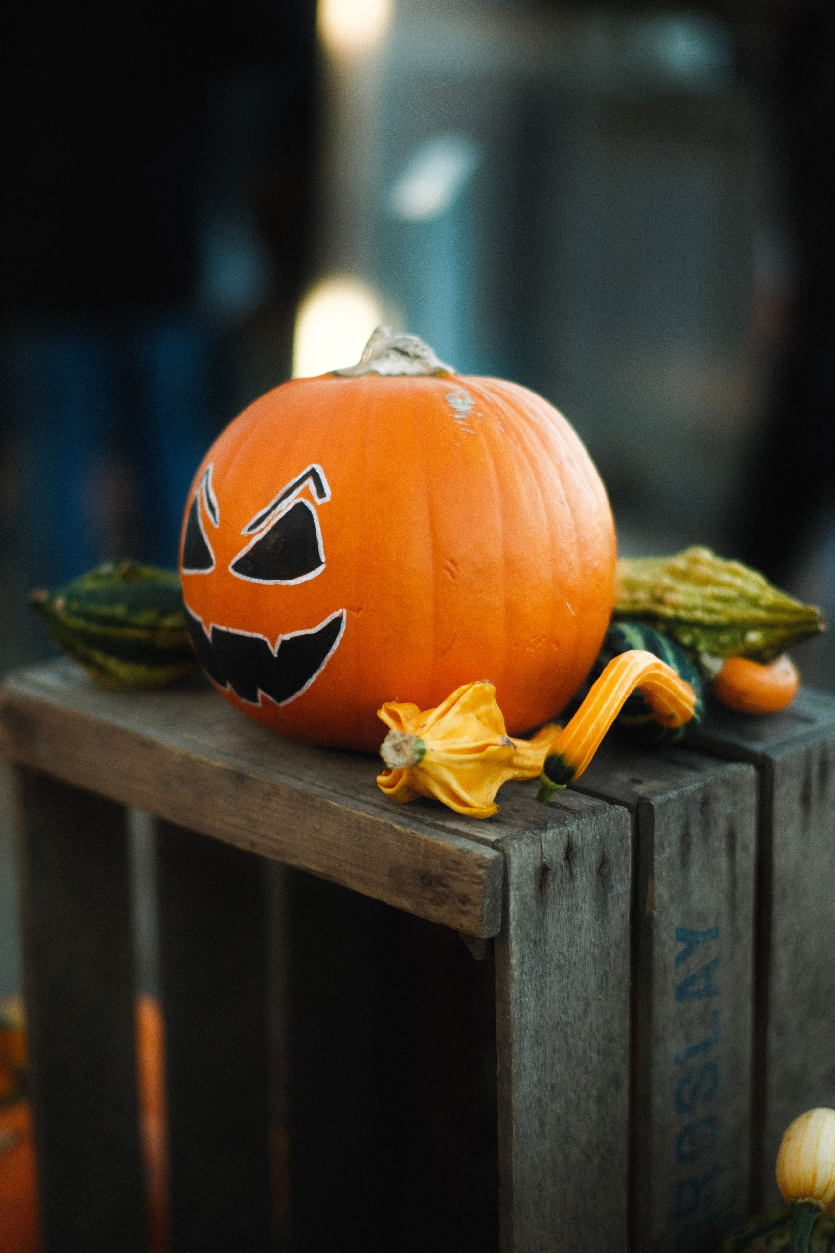 A spooky jack-o'-lantern sits atop a rustic crate with gourds, embodying Halloween festivities.