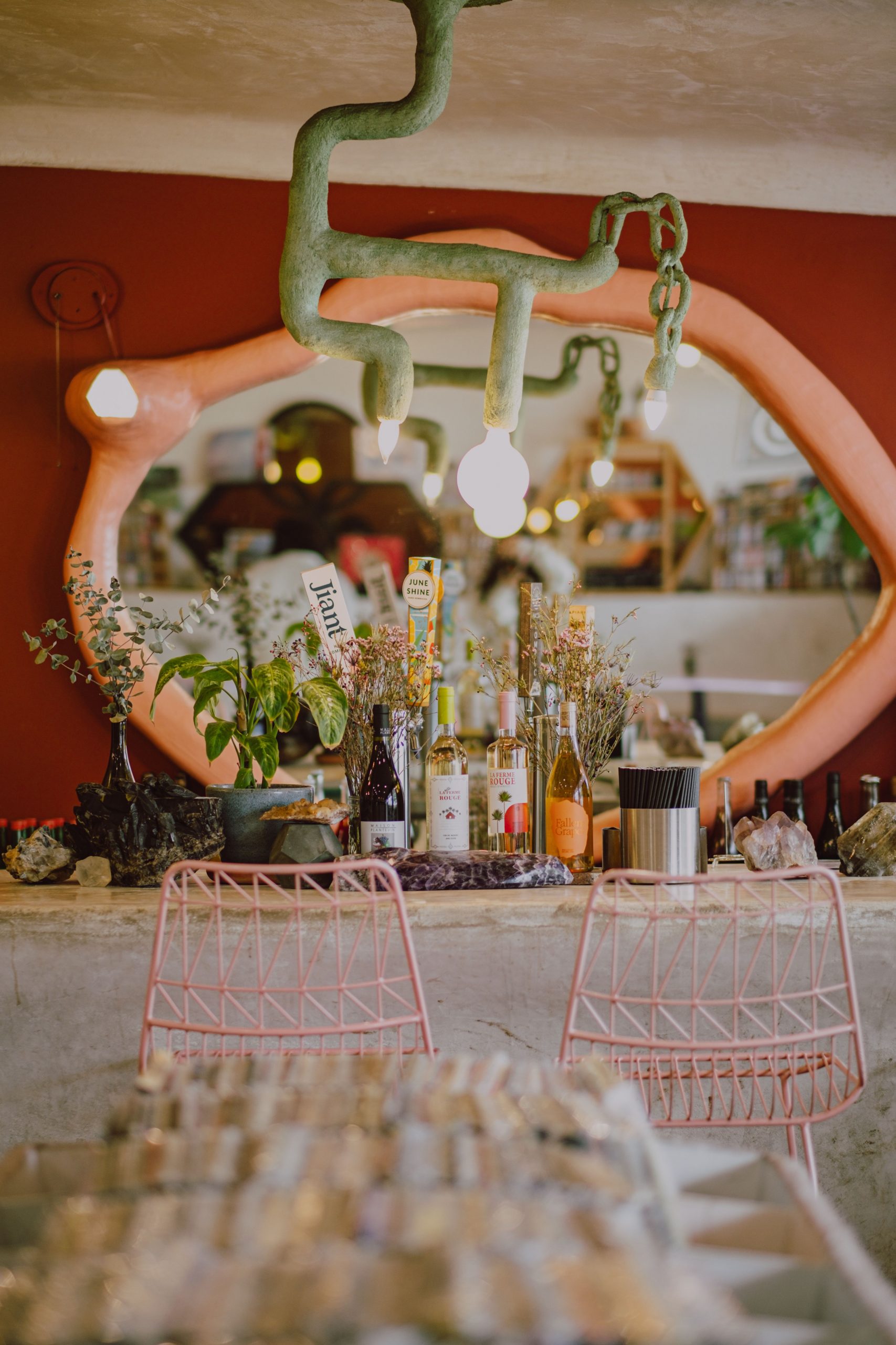 A vibrant dining space featuring pink chairs, eclectic decor, and lush greenery.