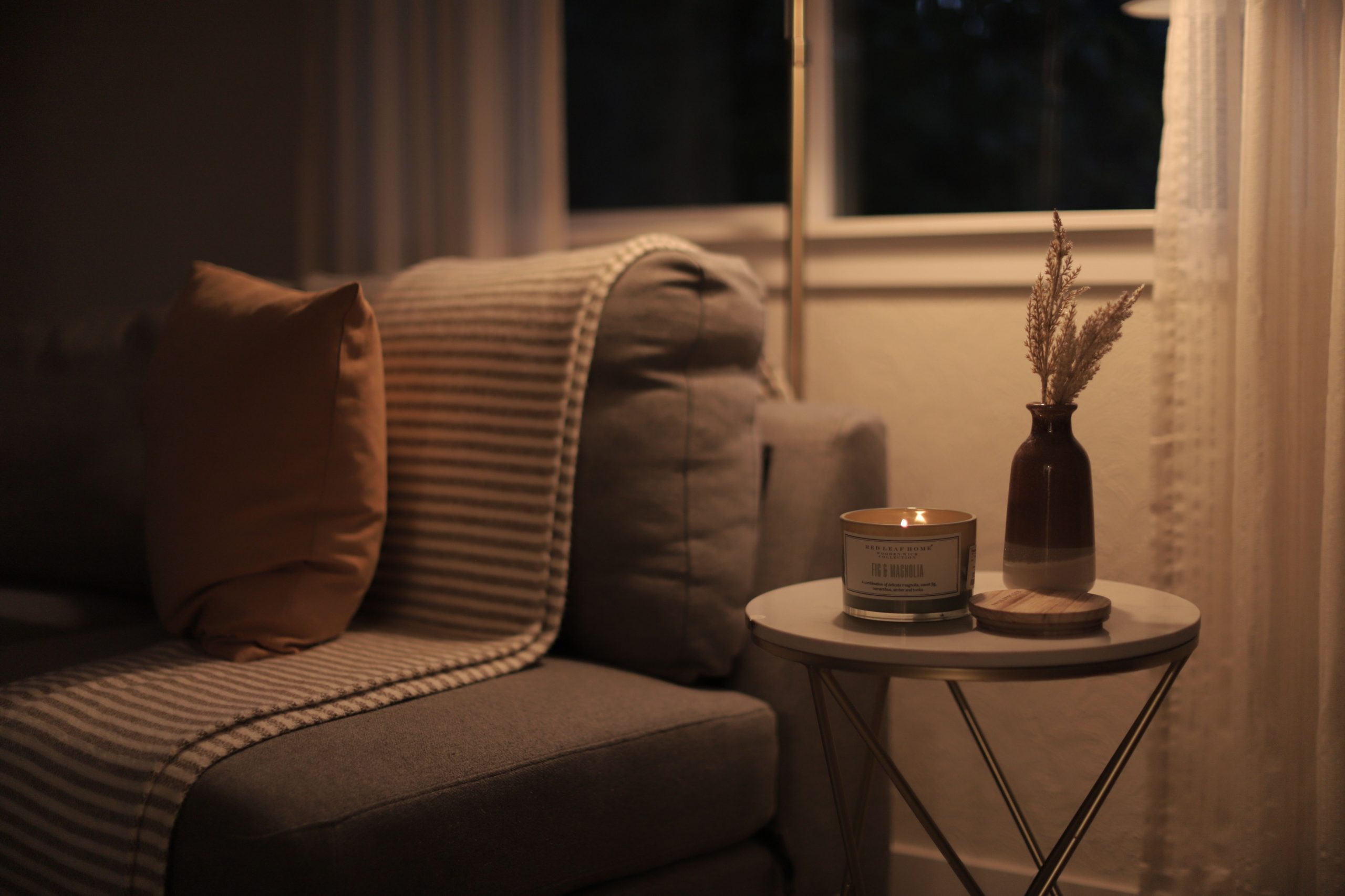 A warm and inviting living room scene featuring a lit candle, sofa, and decorative elements.