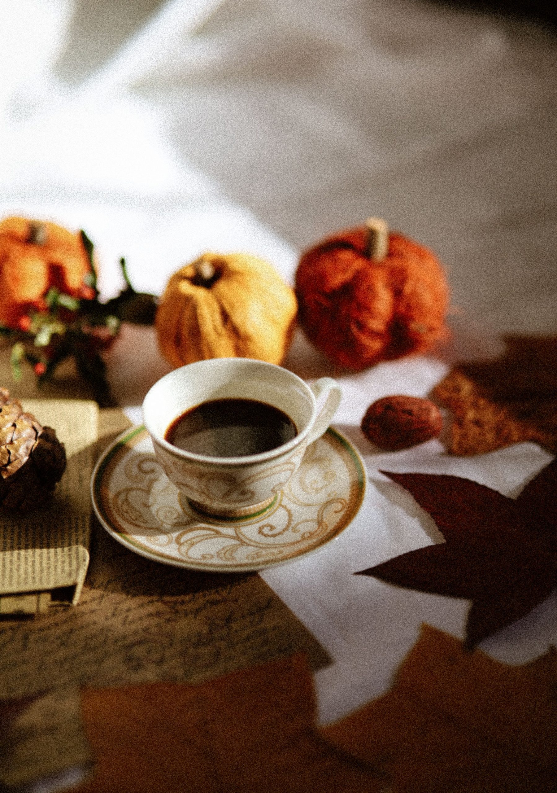 A warm autumn scene featuring a coffee cup among pumpkins and fall leaves, emanating cozy vibes.