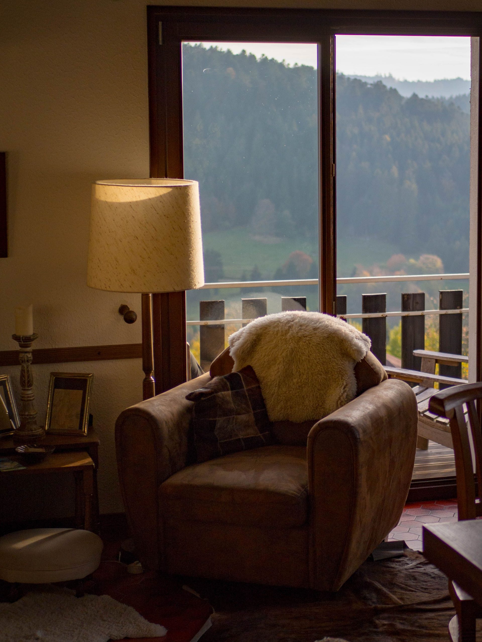 A warm living room with a cozy chair by a glass door overlooking mountains.