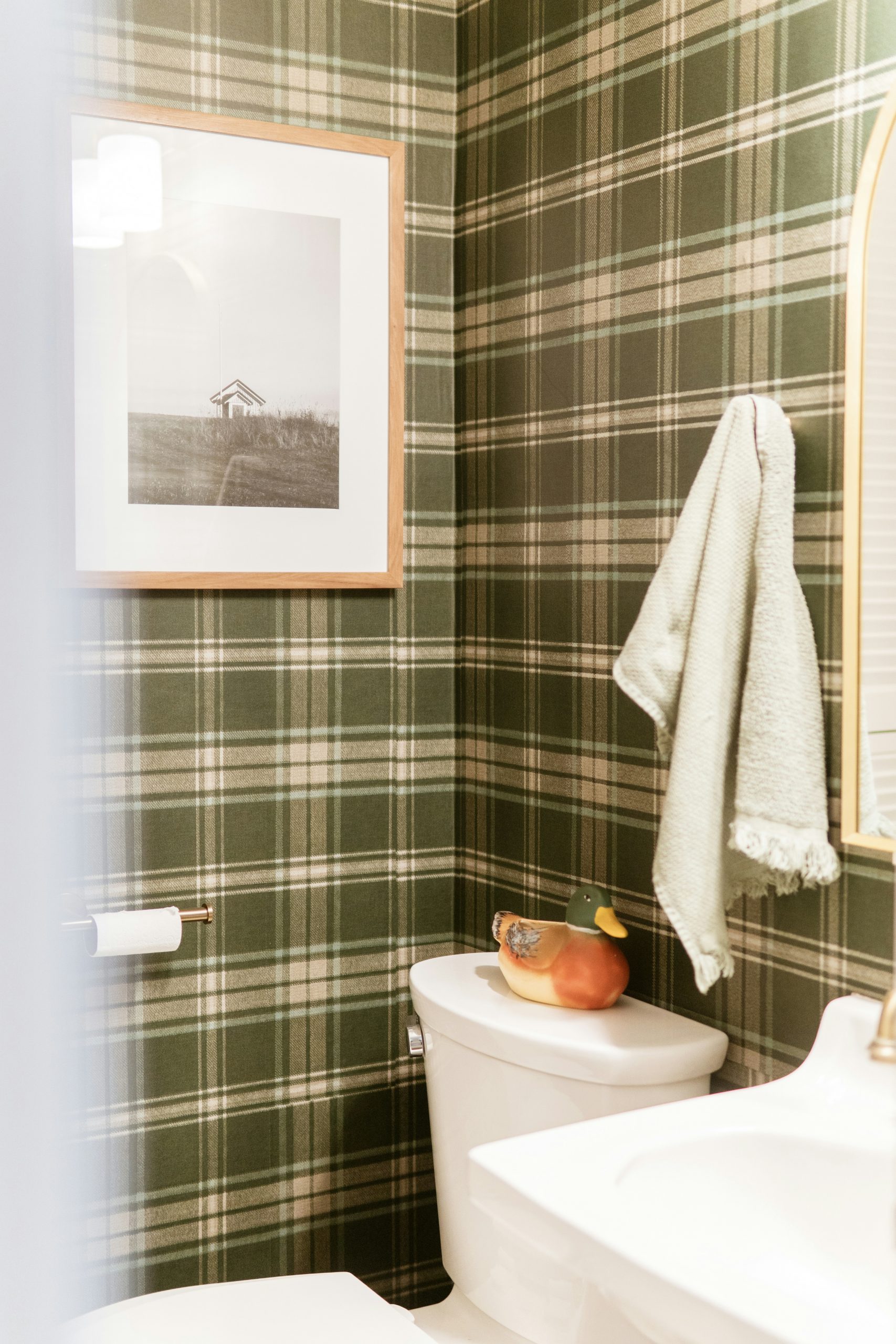 Bathroom with green plaid wallpaper and framed art