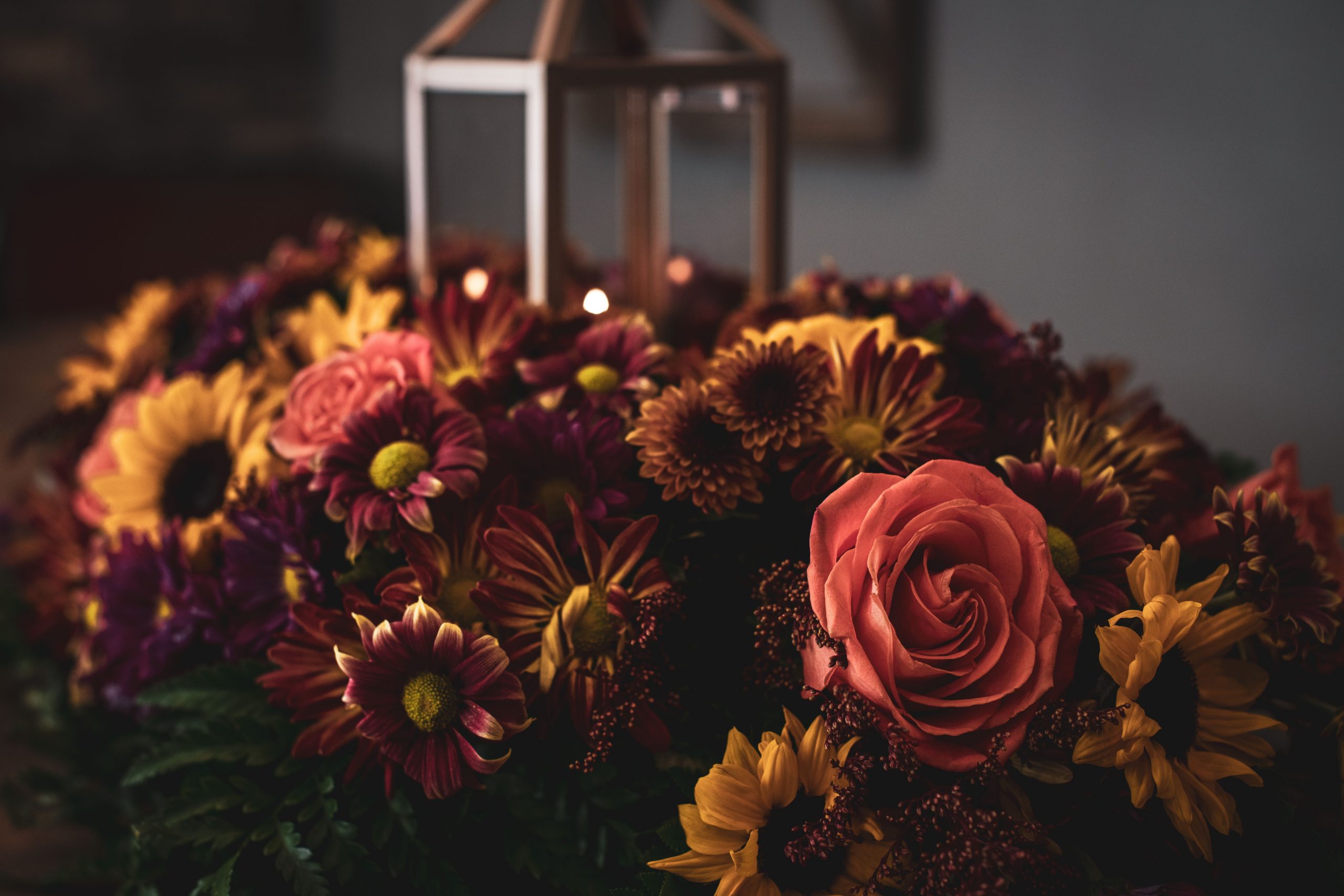 Beautiful autumn floral arrangement featuring chrysanthemums and roses with a decorative lantern.