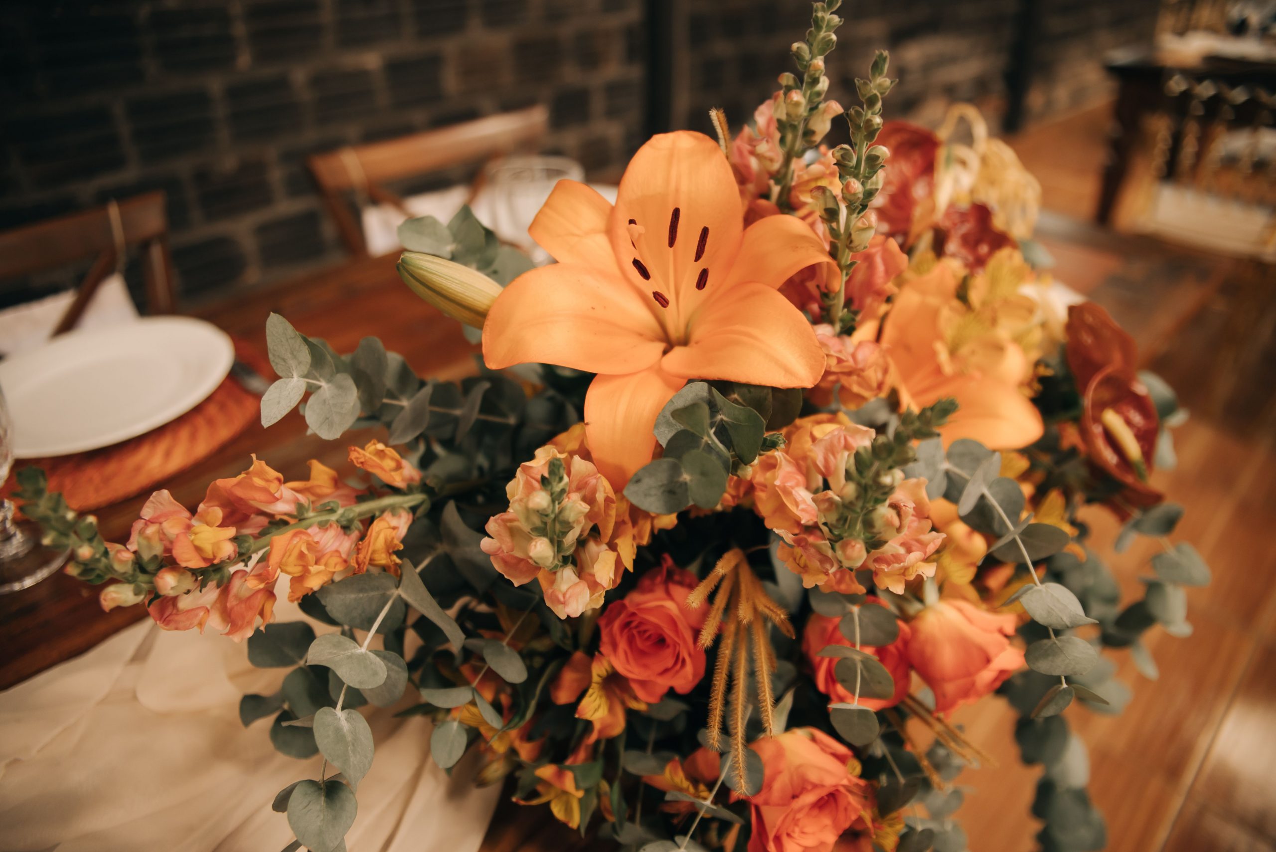 Beautiful flower arrangement with orange lilies and roses, perfect for banquet or event decor.