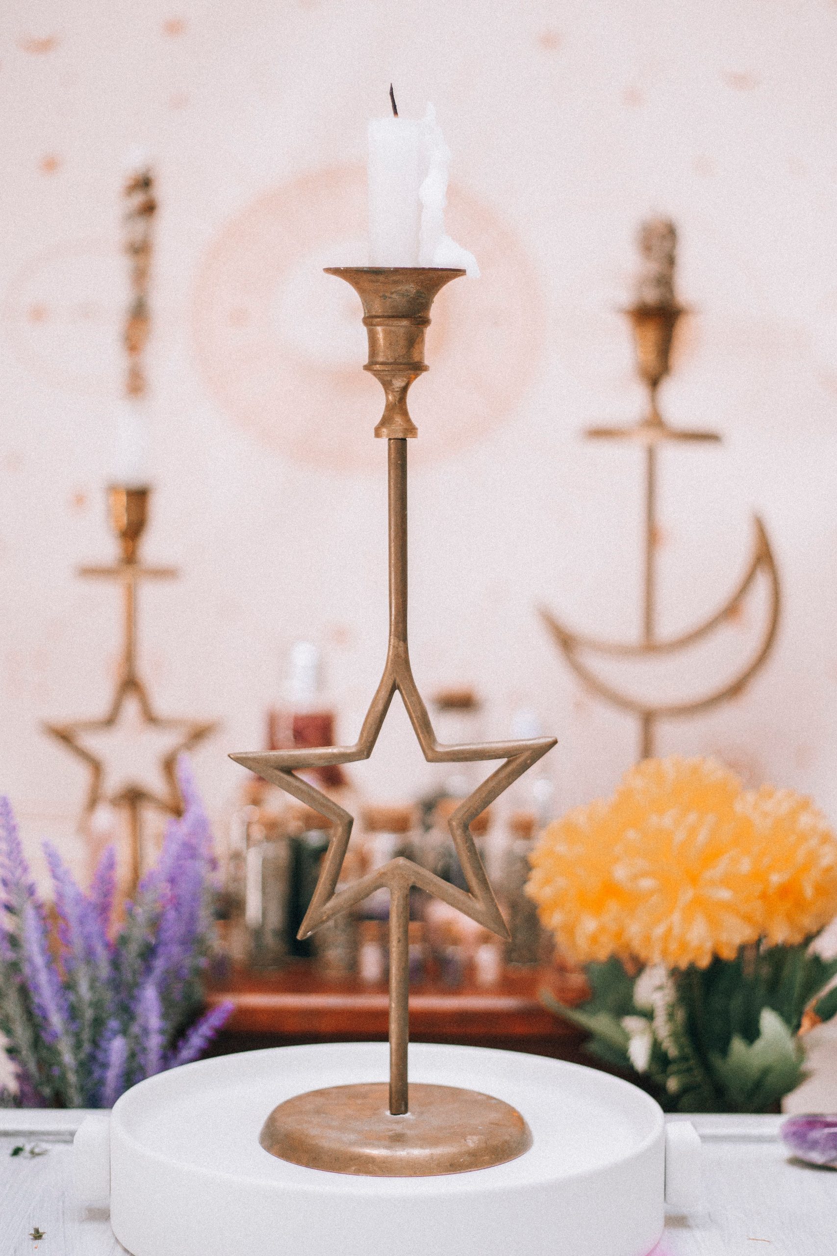 Brass star-shaped candle holder with floral and whimsical background, perfect for boho decor.