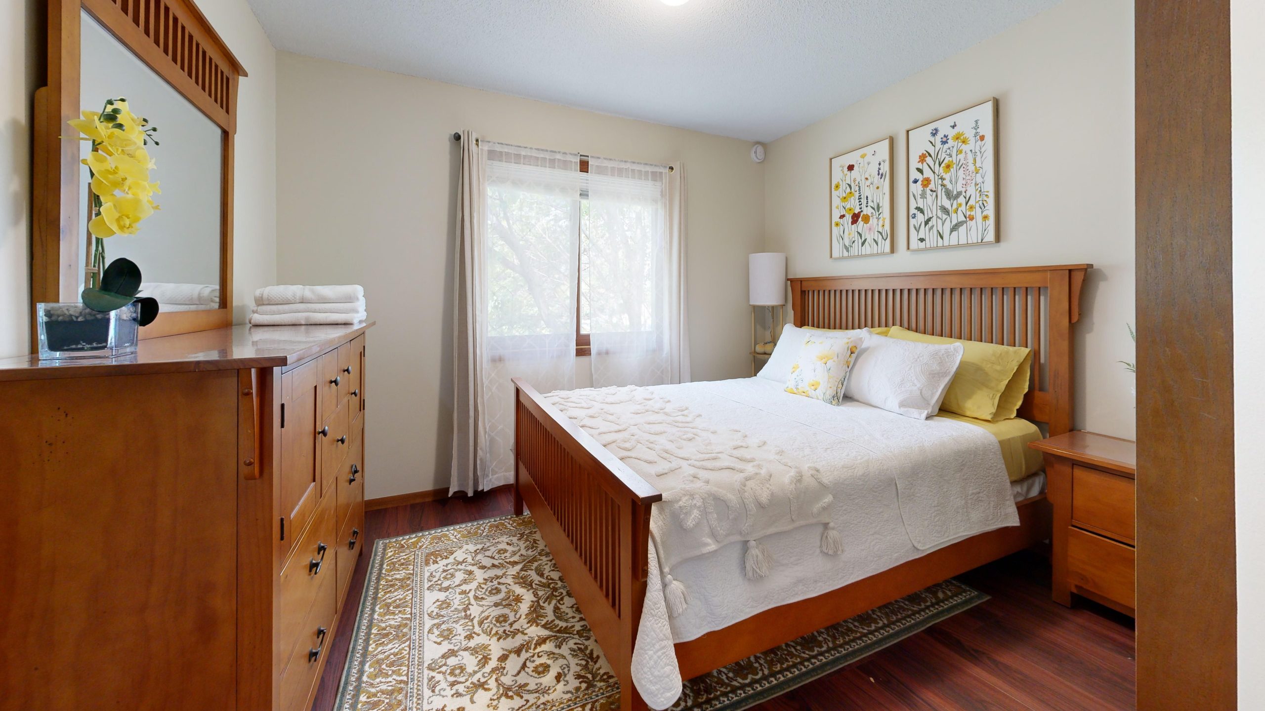 Bright, cozy bedroom with wooden furniture and floral decor.