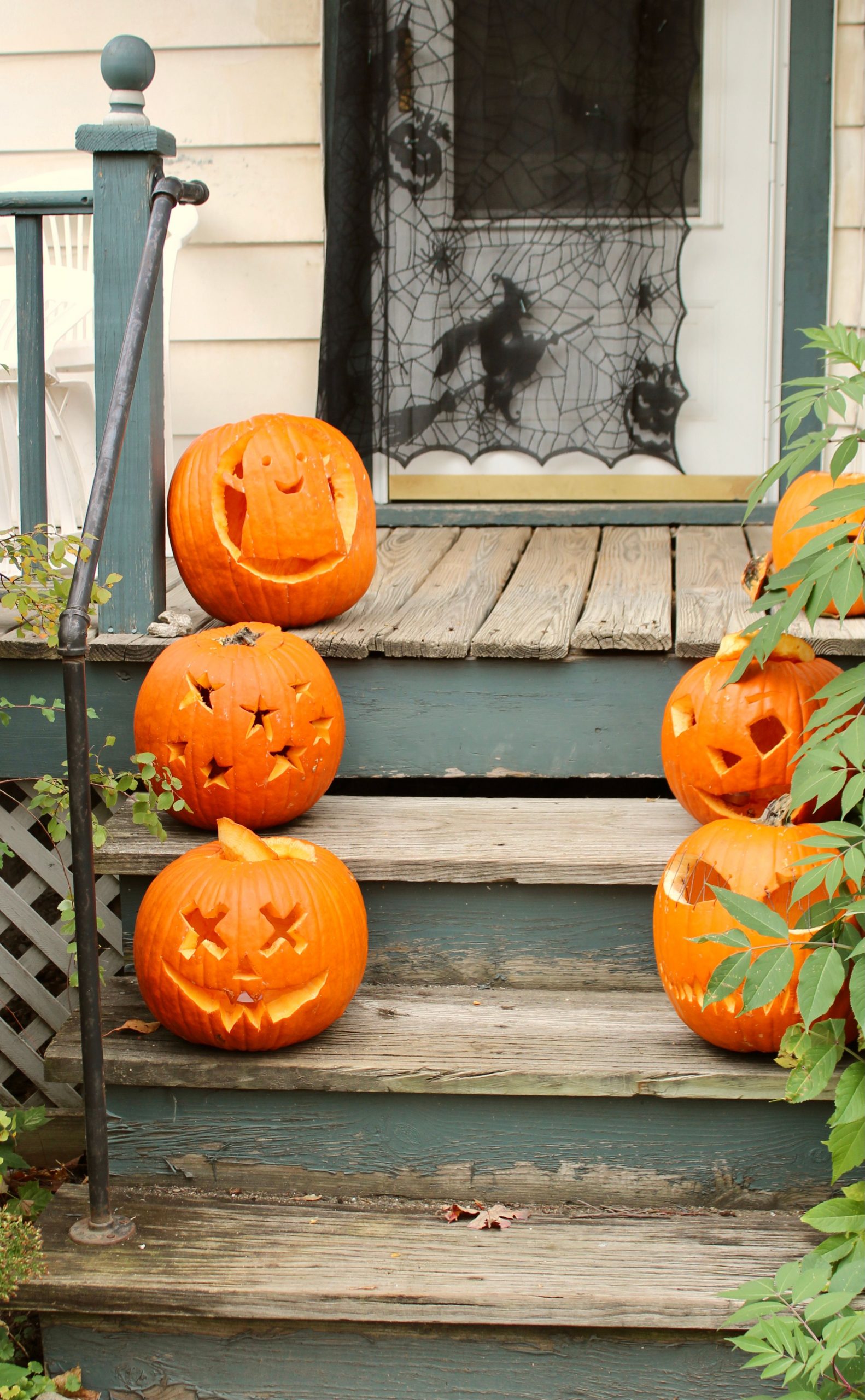 Carved pumpkins on a porch with cobweb decor, celebrating Halloween in Burlington, VT.