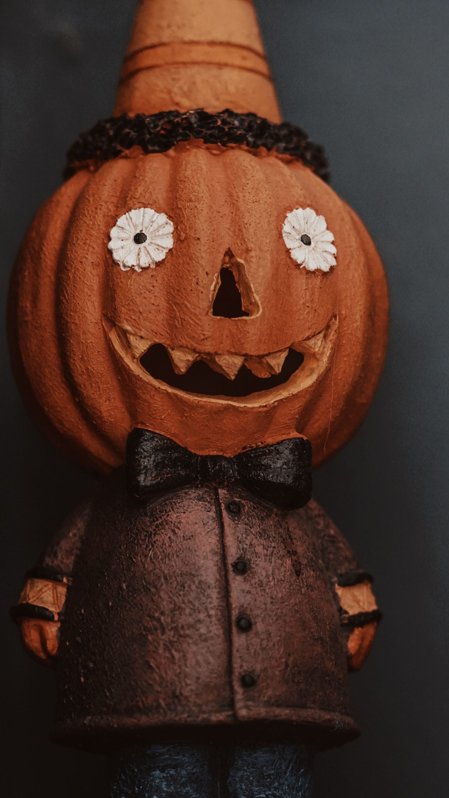 Close-up of a carved pumpkin figurine dressed in a coat for Halloween decoration.