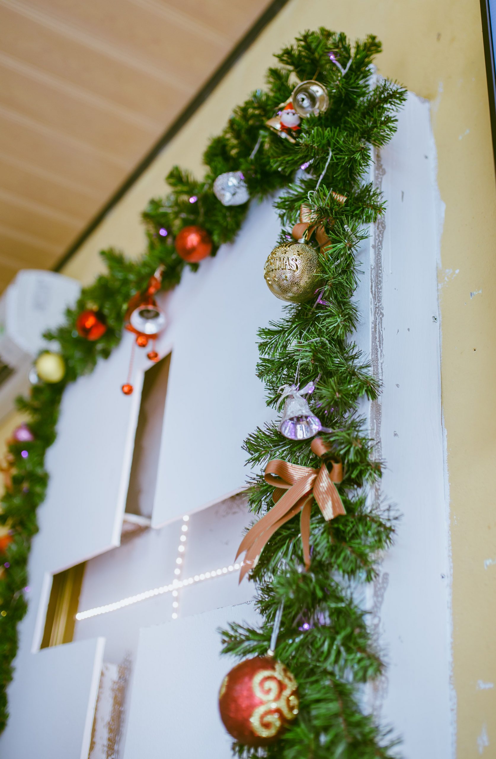 Close-up of a festive Christmas garland with colorful ornaments and pine foliage indoors.